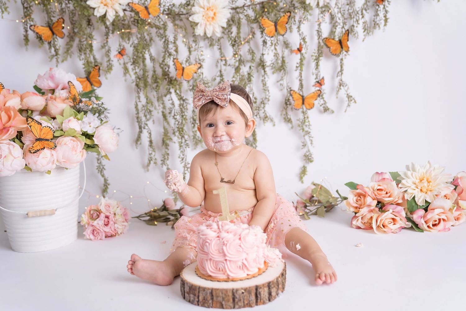 Pink and floral themed cake smash photo session setup with delicate decorations and soft lighting. San Diego cake smash photographer
