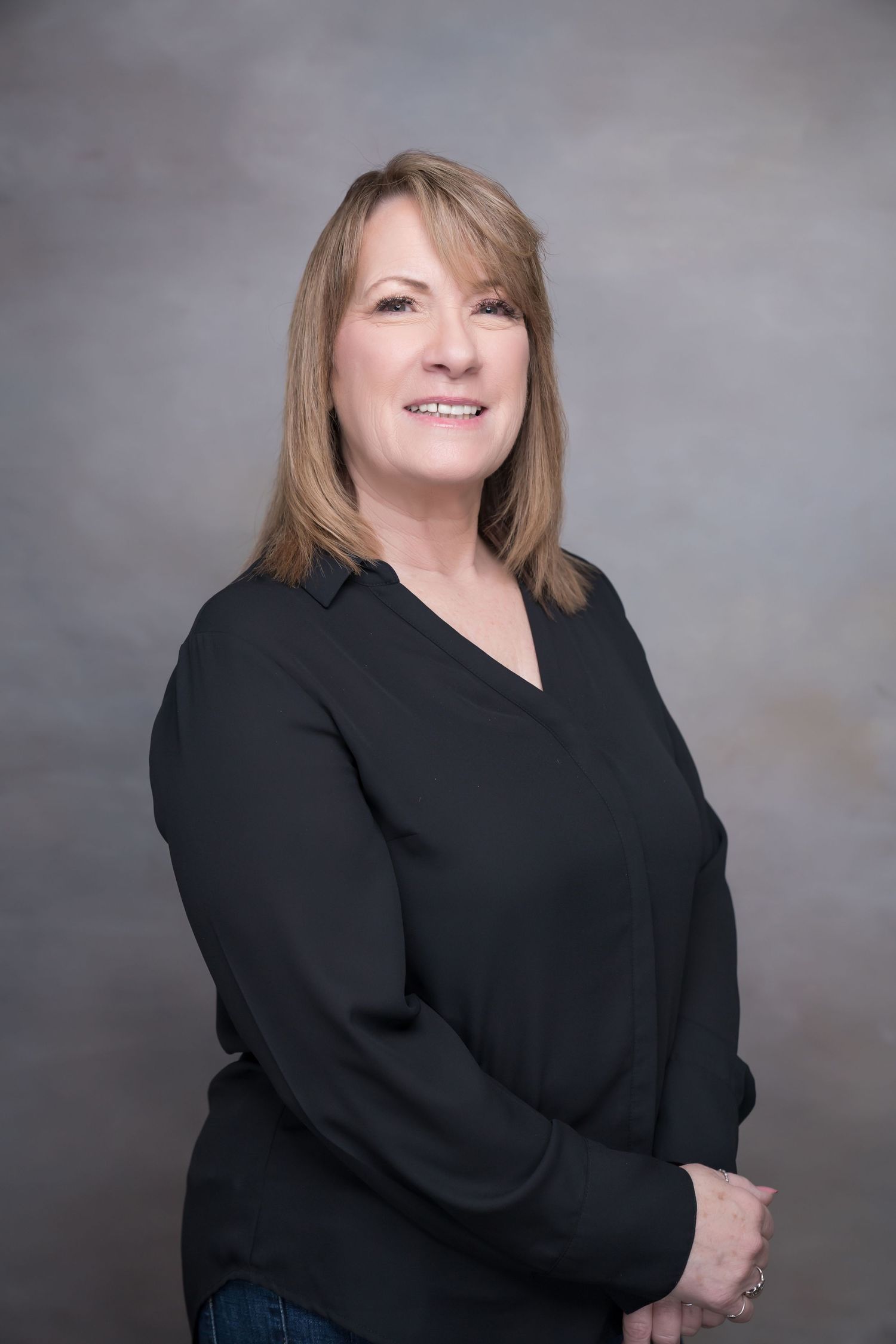 Professional portrait of woman in black business attire against neutral studio background
