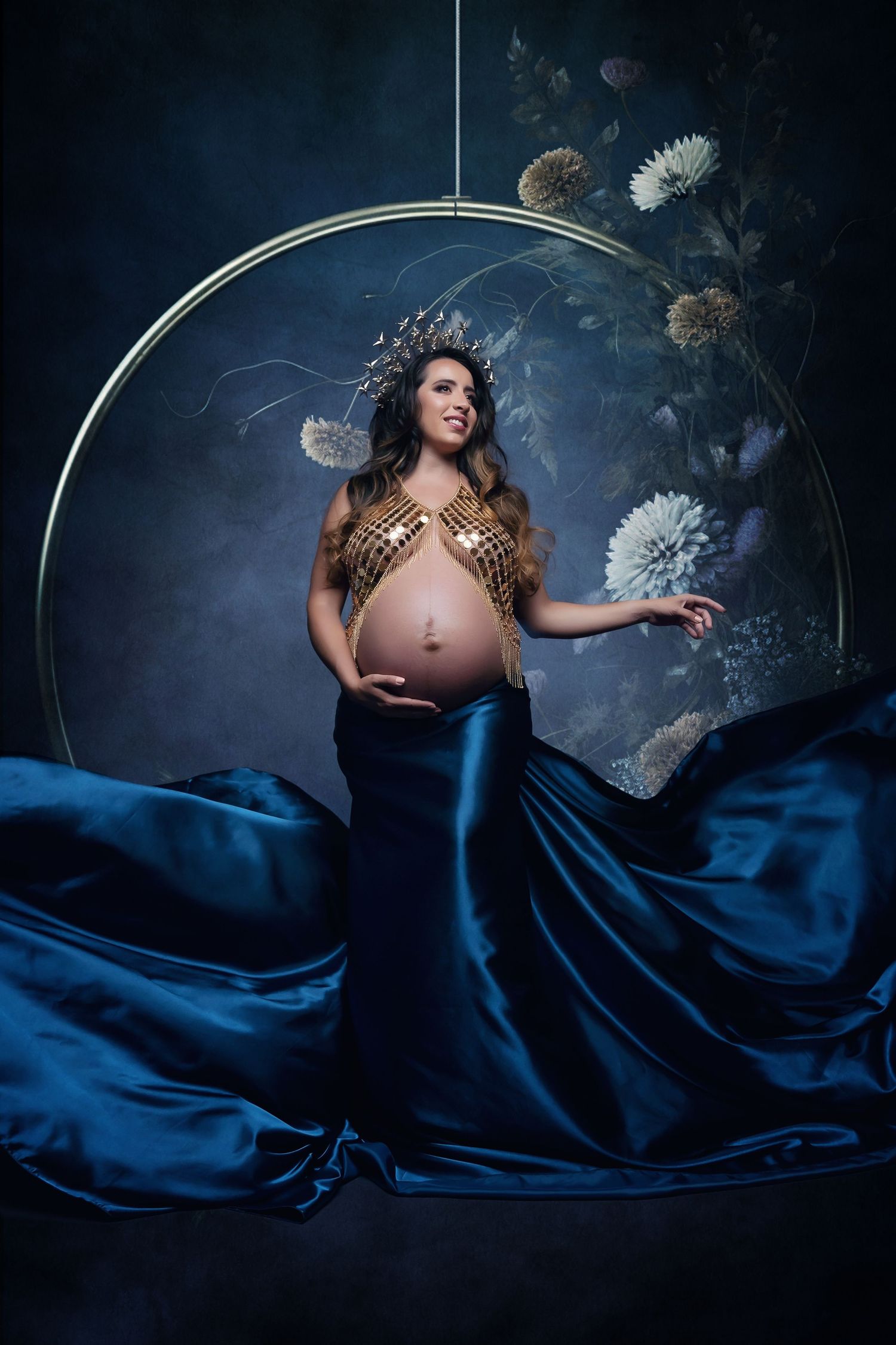 San Diego Maternity Photographer captures Artistic maternity photo with navy blue silk fabric and dandelion decorations.