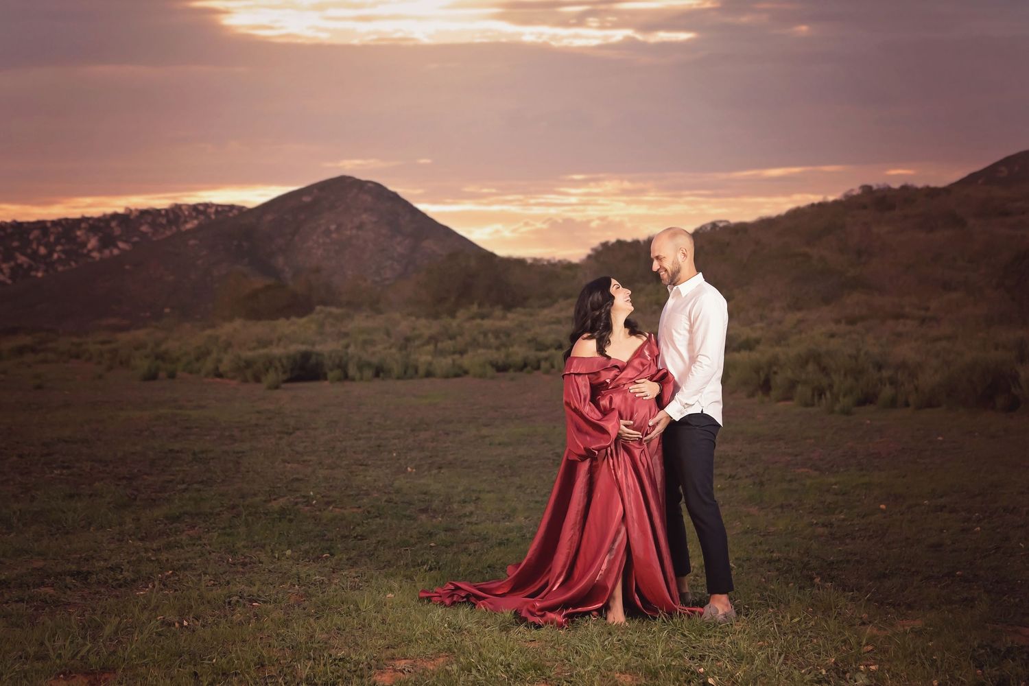Romantic sunset couples photos featuring a flowing red dress in mountain setting. San Diego Maternity Photographer