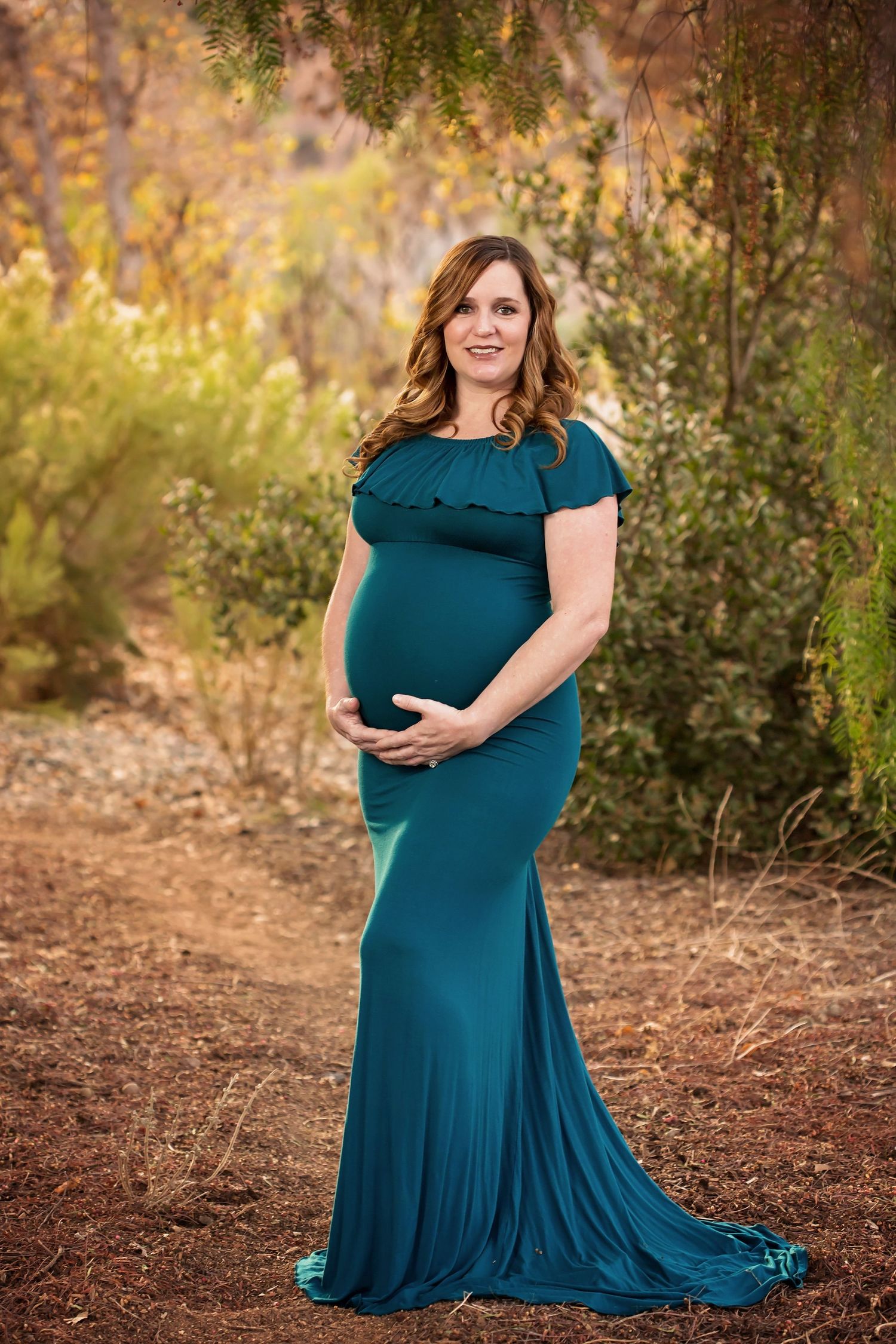 Outdoor maternity portrait session featuring a flowing teal dress in a natural setting. San Diego Maternity Photographer