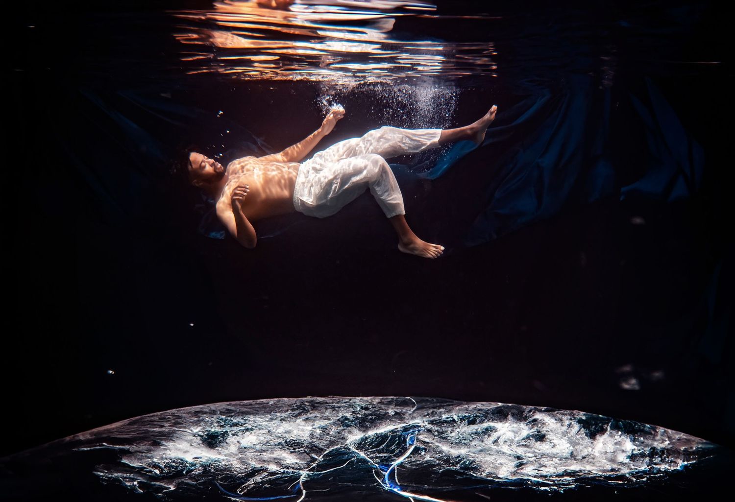 underwater scene with splashing water and floating performer.