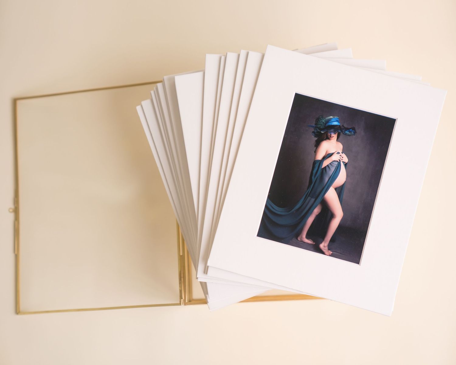 Folio box with matted prints arranged in an artful display on a beige surface. San Diego Maternity Photographer