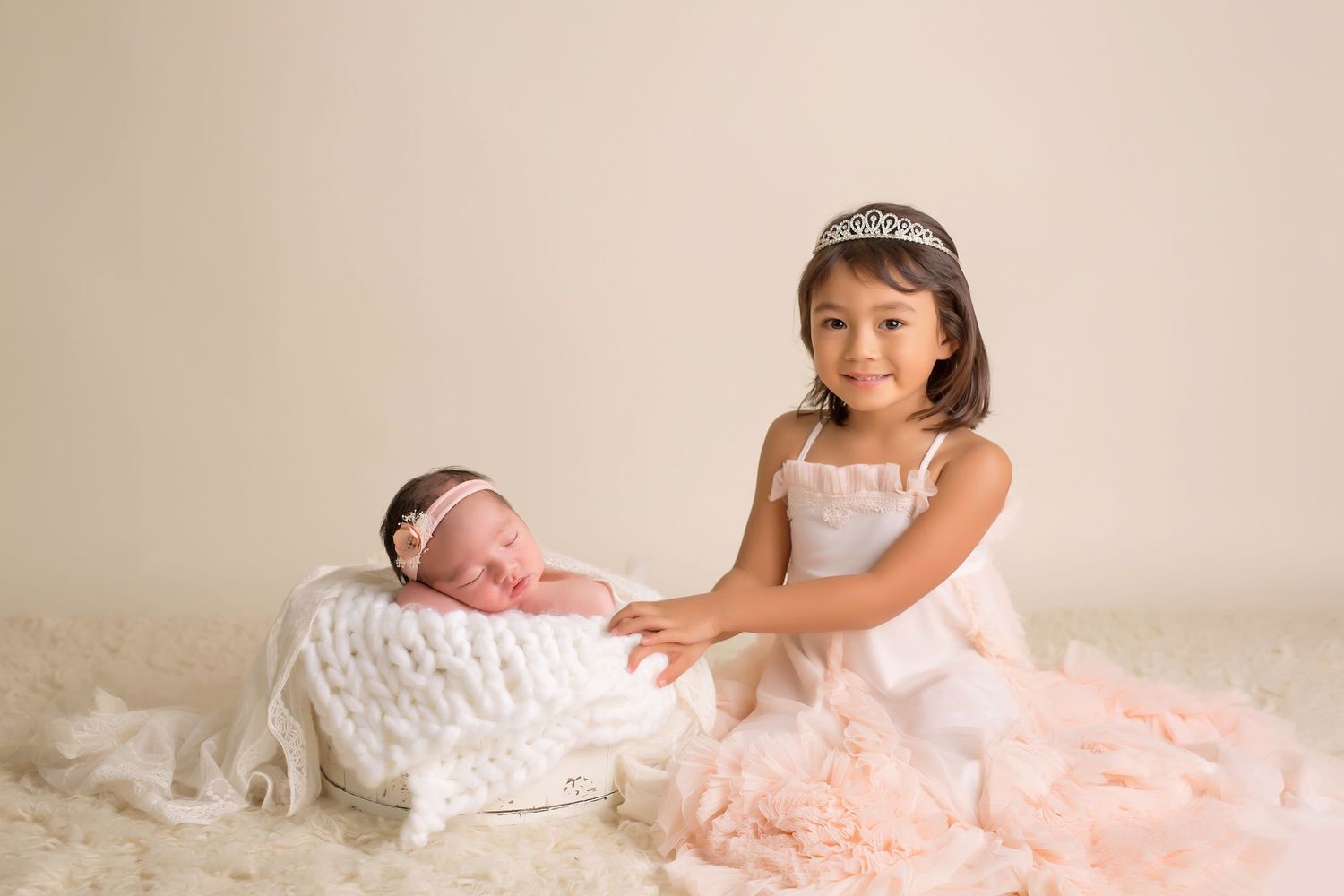 Baby photography session with soft pink and cream colored props and blankets. San Diego Newborn Photographer