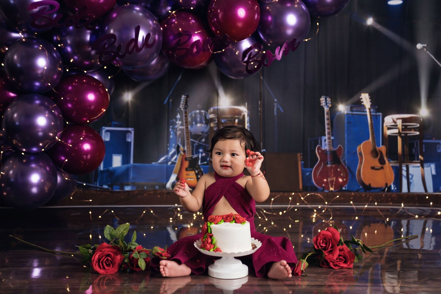 Magical balloon display with burgundy and purple hues in dimly lit setting. San Diego cake smash photographer