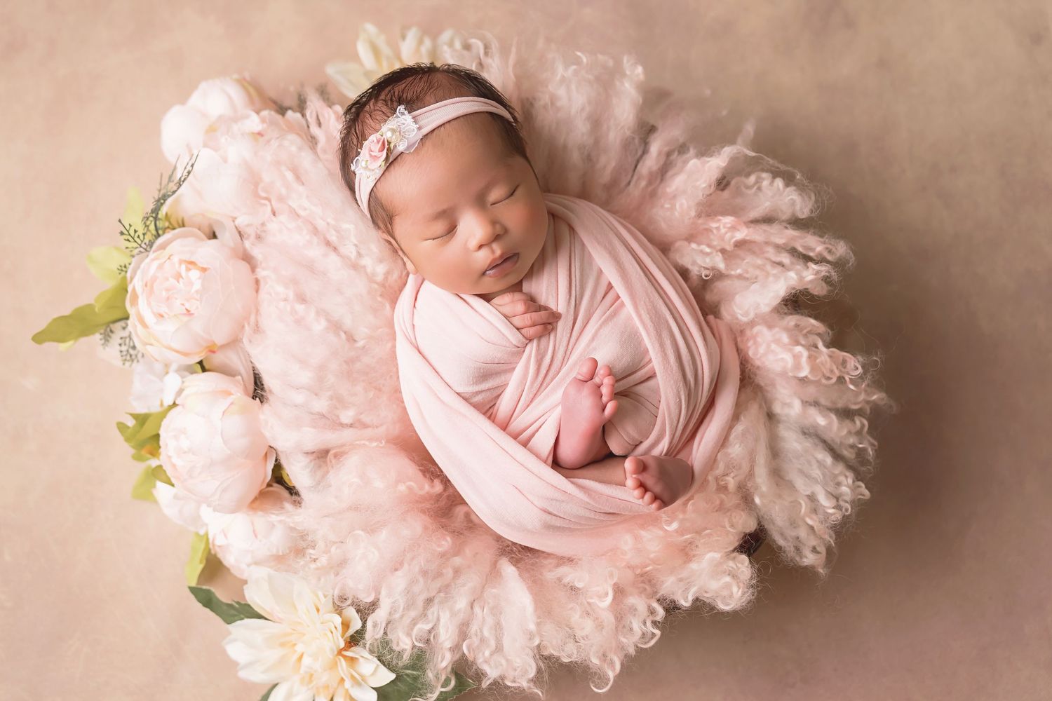 Newborn photography session featuring soft pink tulle and white floral arrangements. San Diego Newborn Photographer