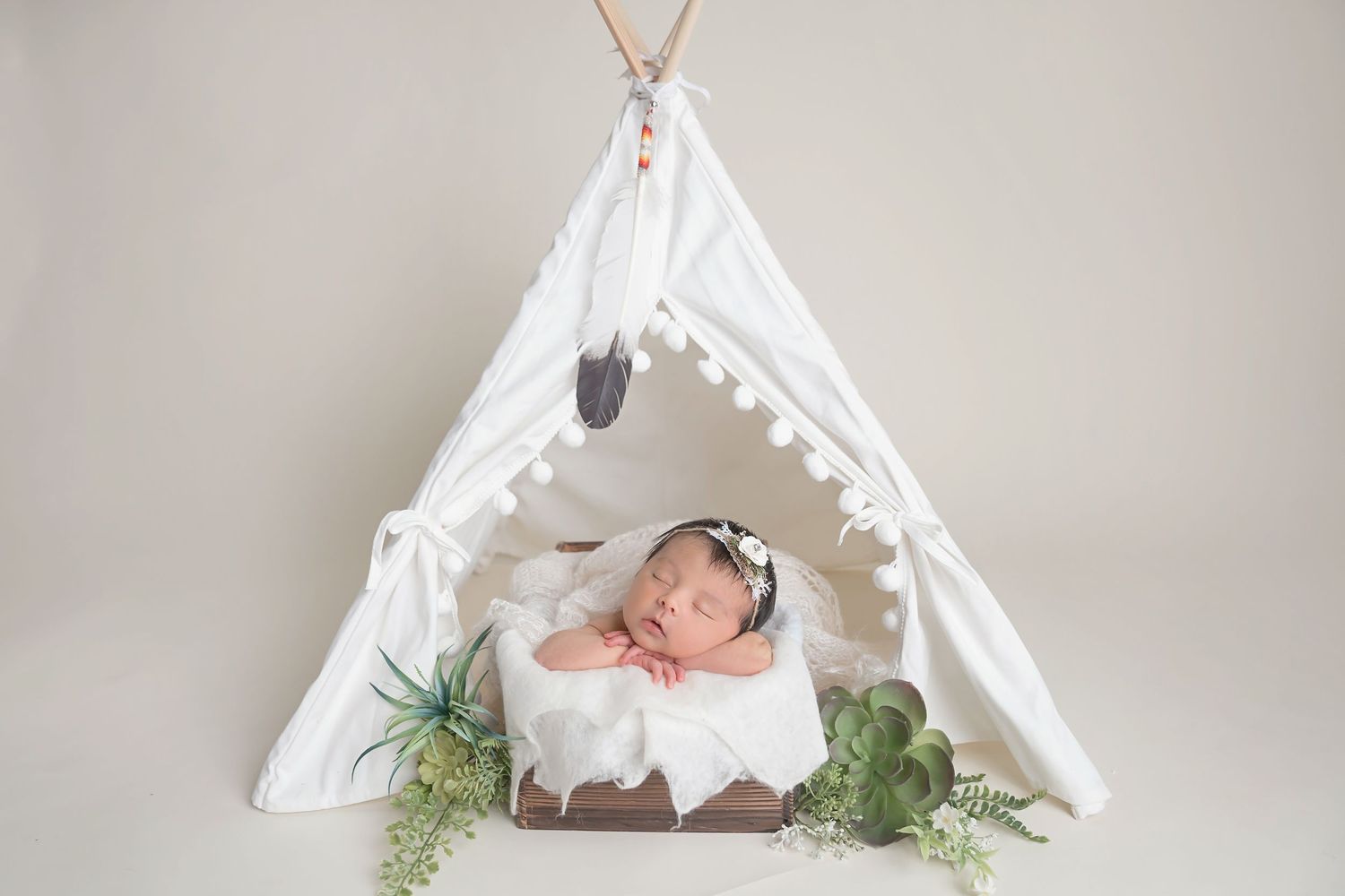 Sleeping baby in white teepee tent with greenery and decorative accents. San Diego Newborn Photographer