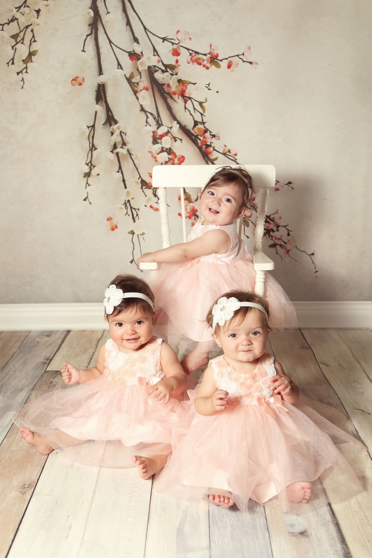 Sweet portrait session with pink dresses and cherry blossom branches on white wooden floor. San Diego cake smash photographer