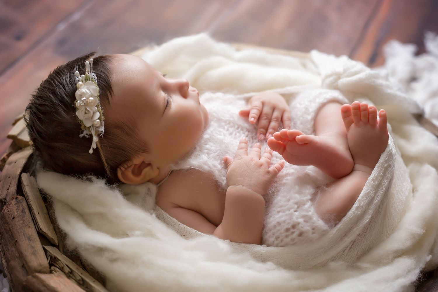 Newborn baby sleeping peacefully in soft white blankets with delicate lace details. San Diego Newborn Photographer