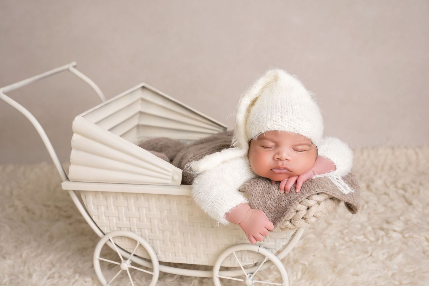 San Diego newborn photographer captures Newborn sleeping in vintage white carriage prop with delicate styling.
