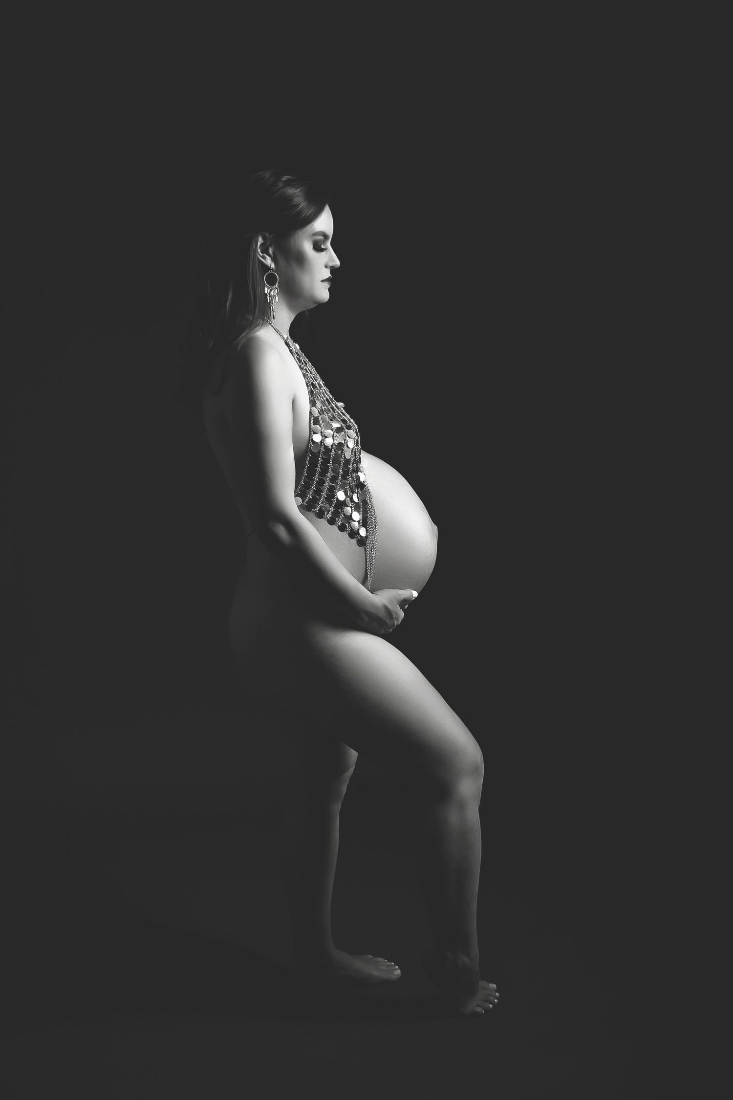Dramatic black and white maternity portrait with side lighting.