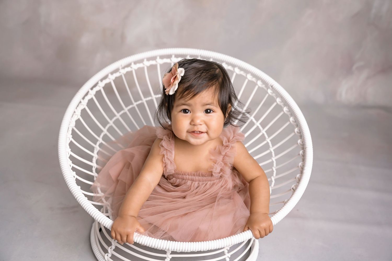 White wicker chair setup with soft lighting and neutral backdrop. San Diego cake smash photographer