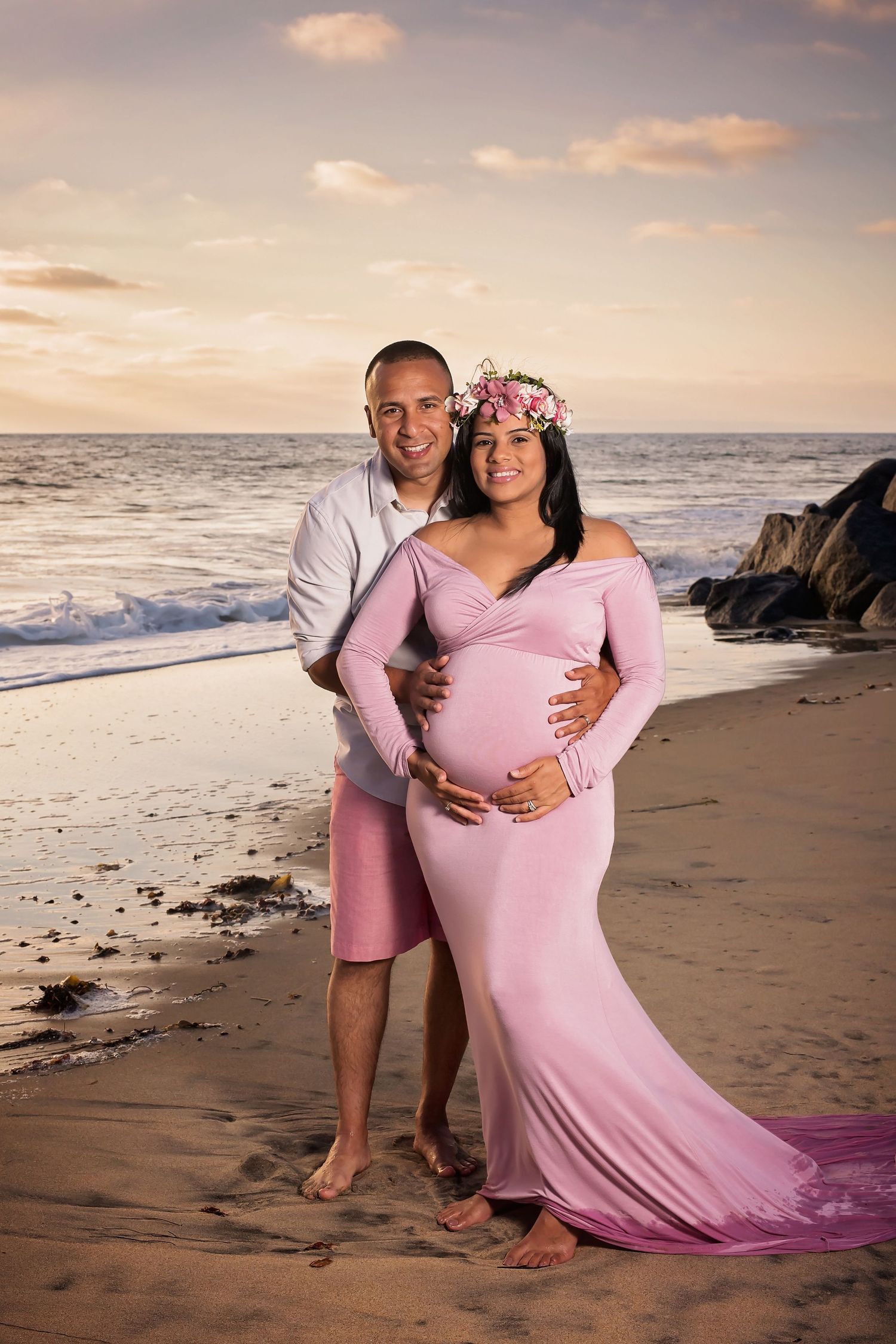 Maternity photo session at sunset on a beach with couple in pink dress and white shirt against ocean backdrop. San Diego Maternity Photograp
