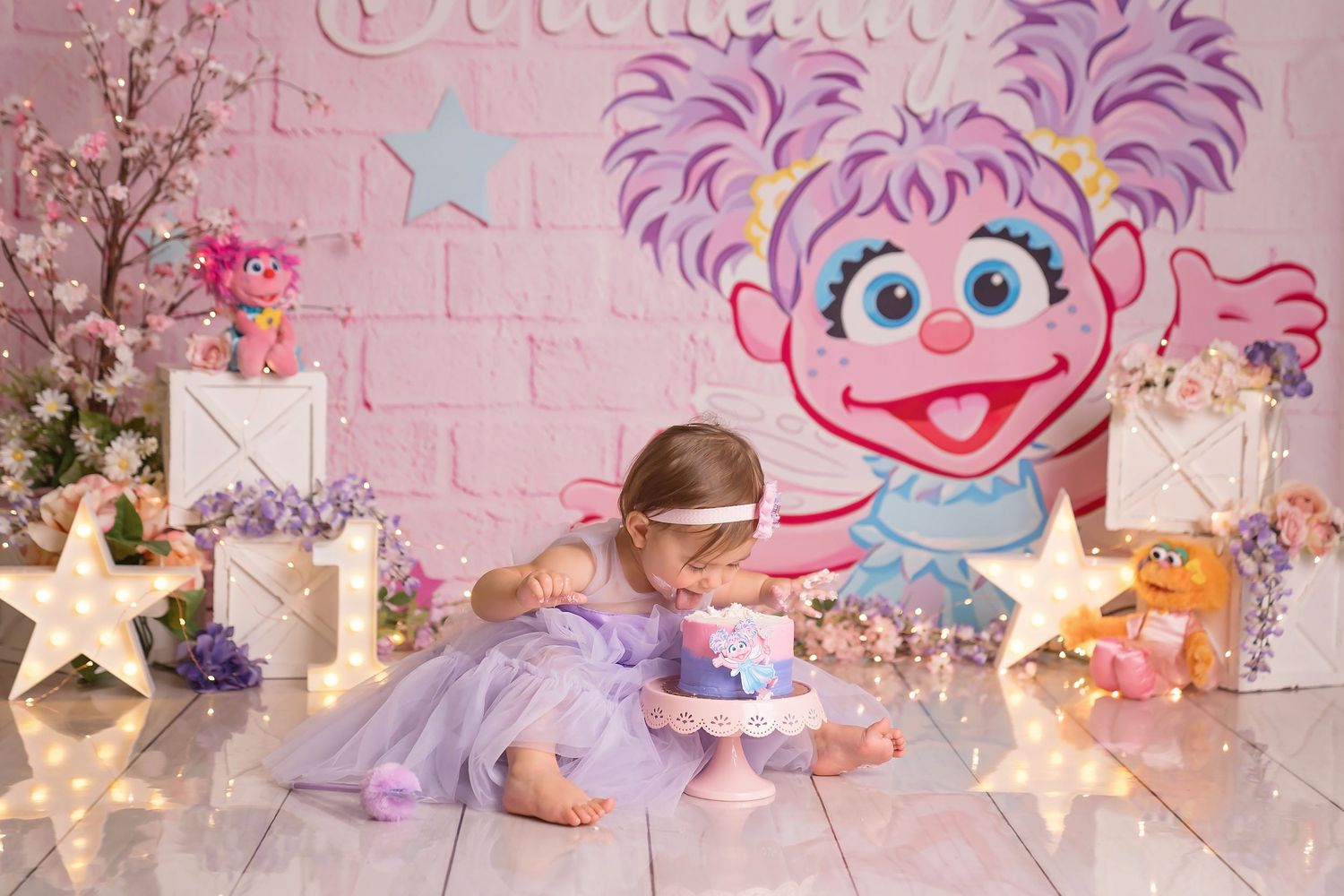 Toddler girl in purple dress celebrates first birthday with Abby Cadabby themed cake smash on white floor.