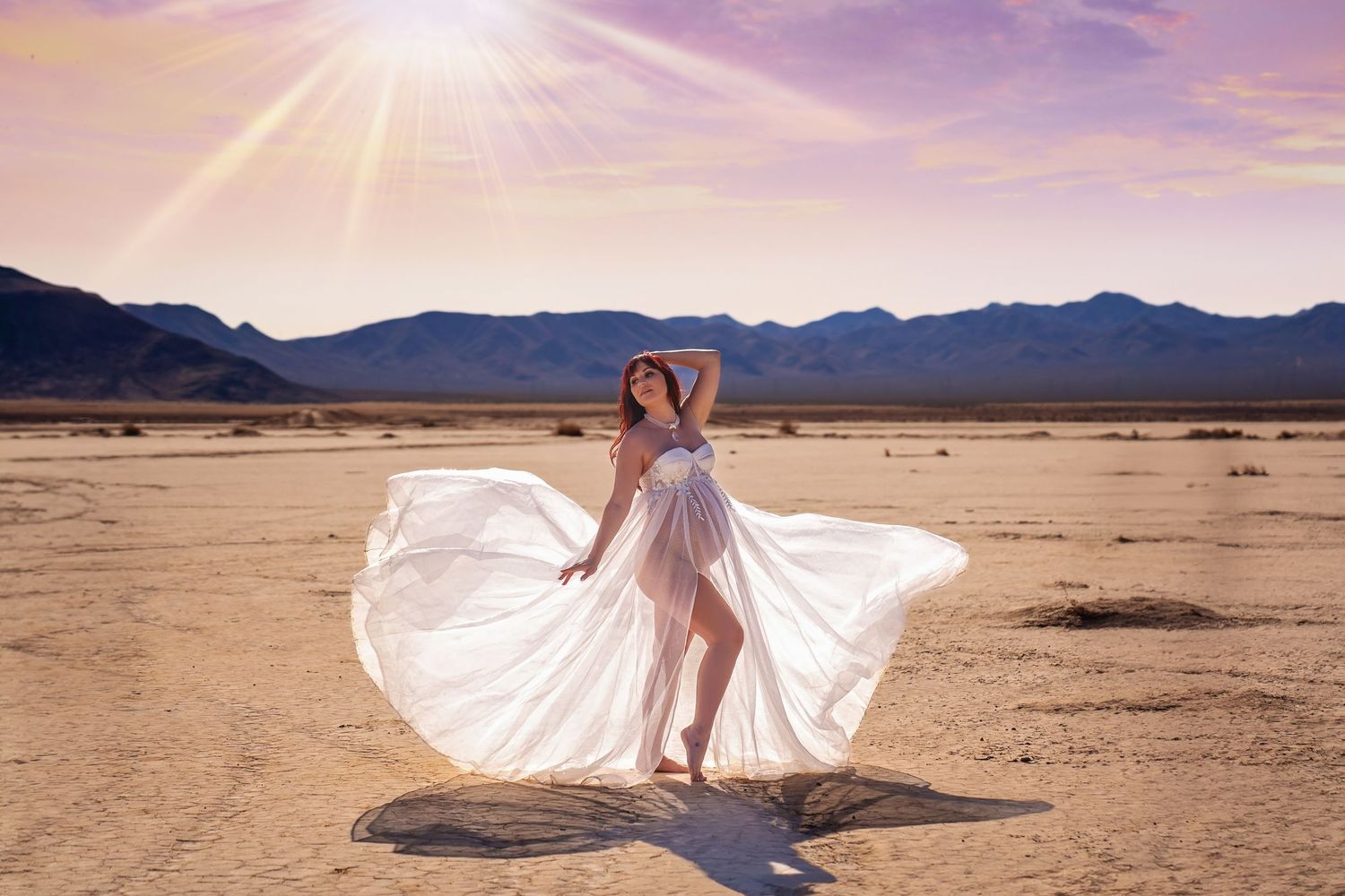 A flowing white dress spins in motion against a desert landscape backdrop. San Diego Maternity Photographer