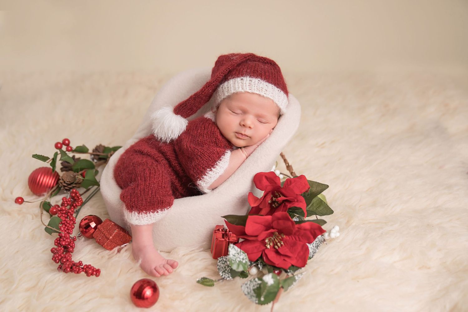 Holiday themed newborn photo with red knit accessories and Christmas decorations. San Diego Newborn Photographer