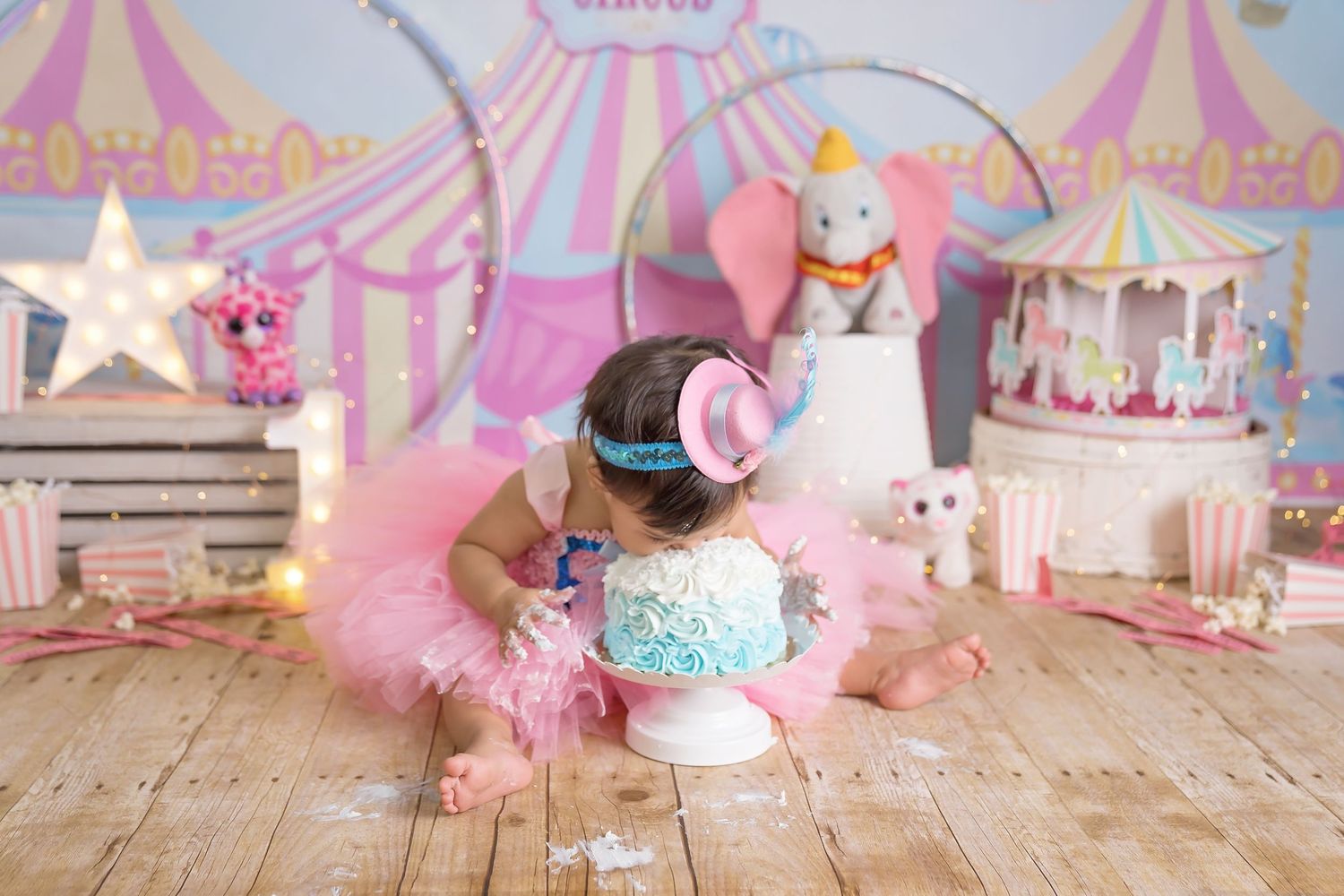 Pink circus themed photo backdrop with carnival tents and wooden floor. San Diego cake smash photographer