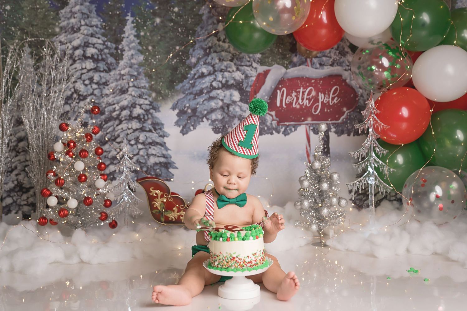Christmas themed photo setup with red and green balloons, snow effects, and holiday decorations.