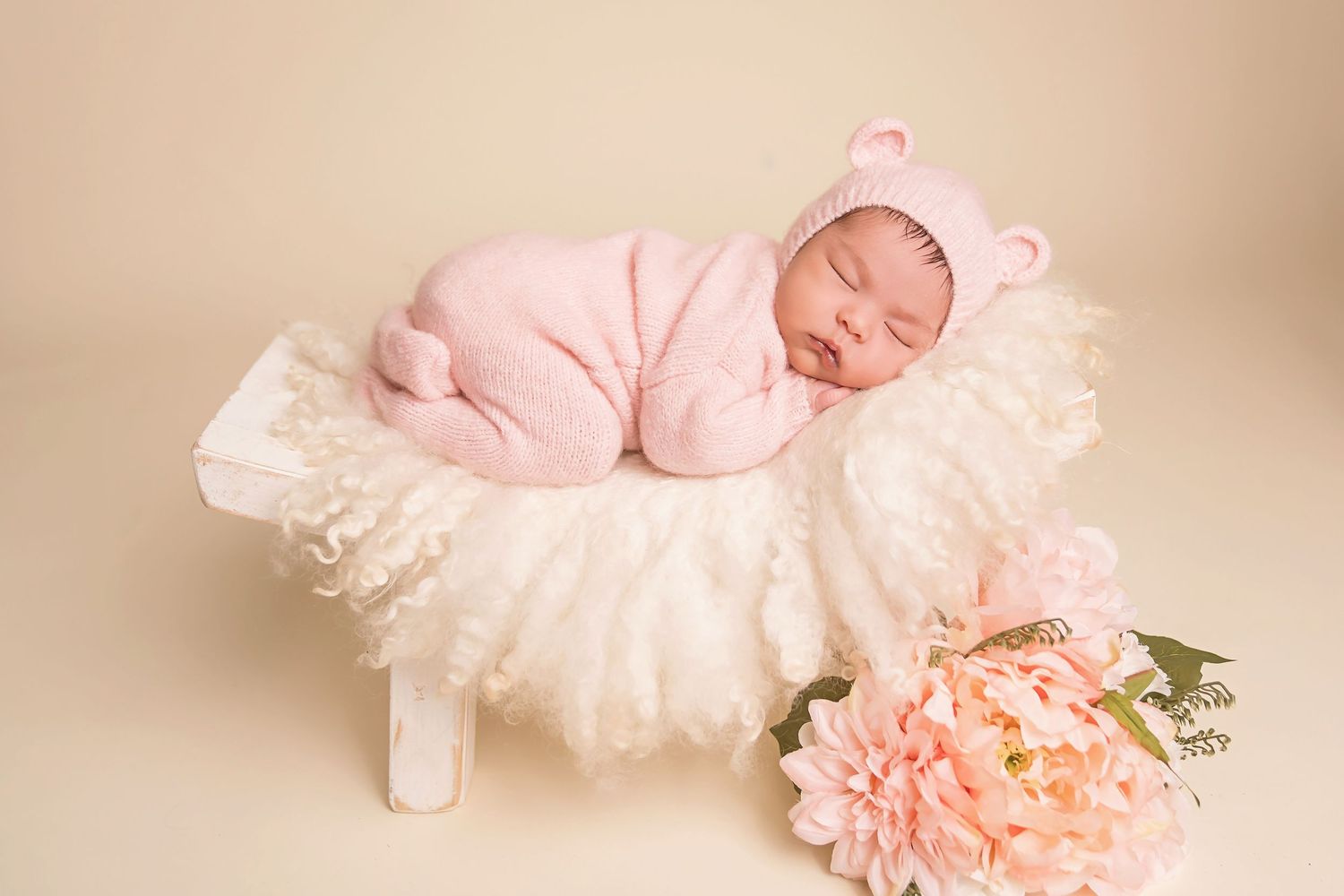 Sleeping baby in pink tulle dress with peach floral accents on cream background. San Diego Newborn Photographer