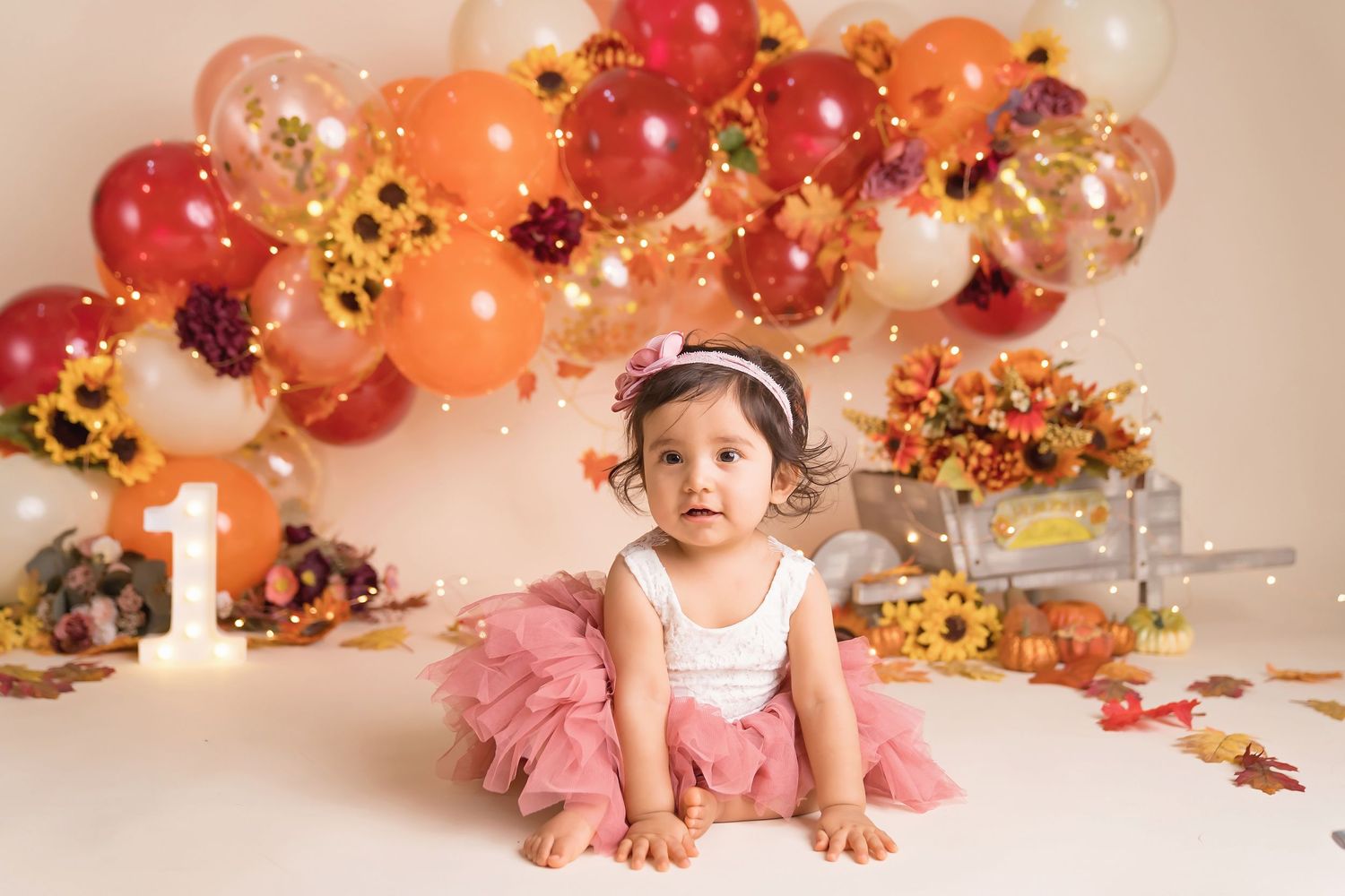Autumn-themed photo setup with orange and gold balloon garland and floral accents.