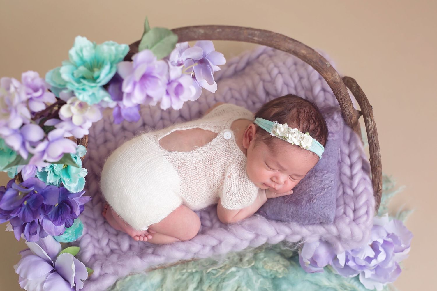 San Diego newborn photographer captures Dreamy newborn setup with purple and mint floral decorations on soft backdrop.