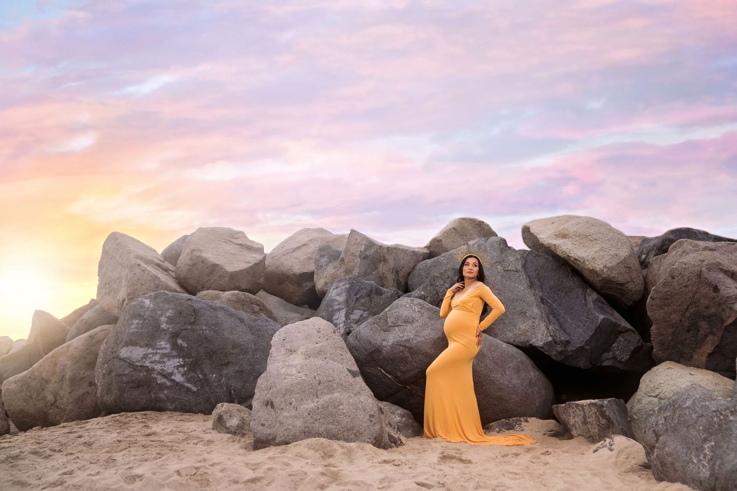 Silhouettes against a pastel sky with large coastal rocks at sunset. San Diego Maternity Photographer
