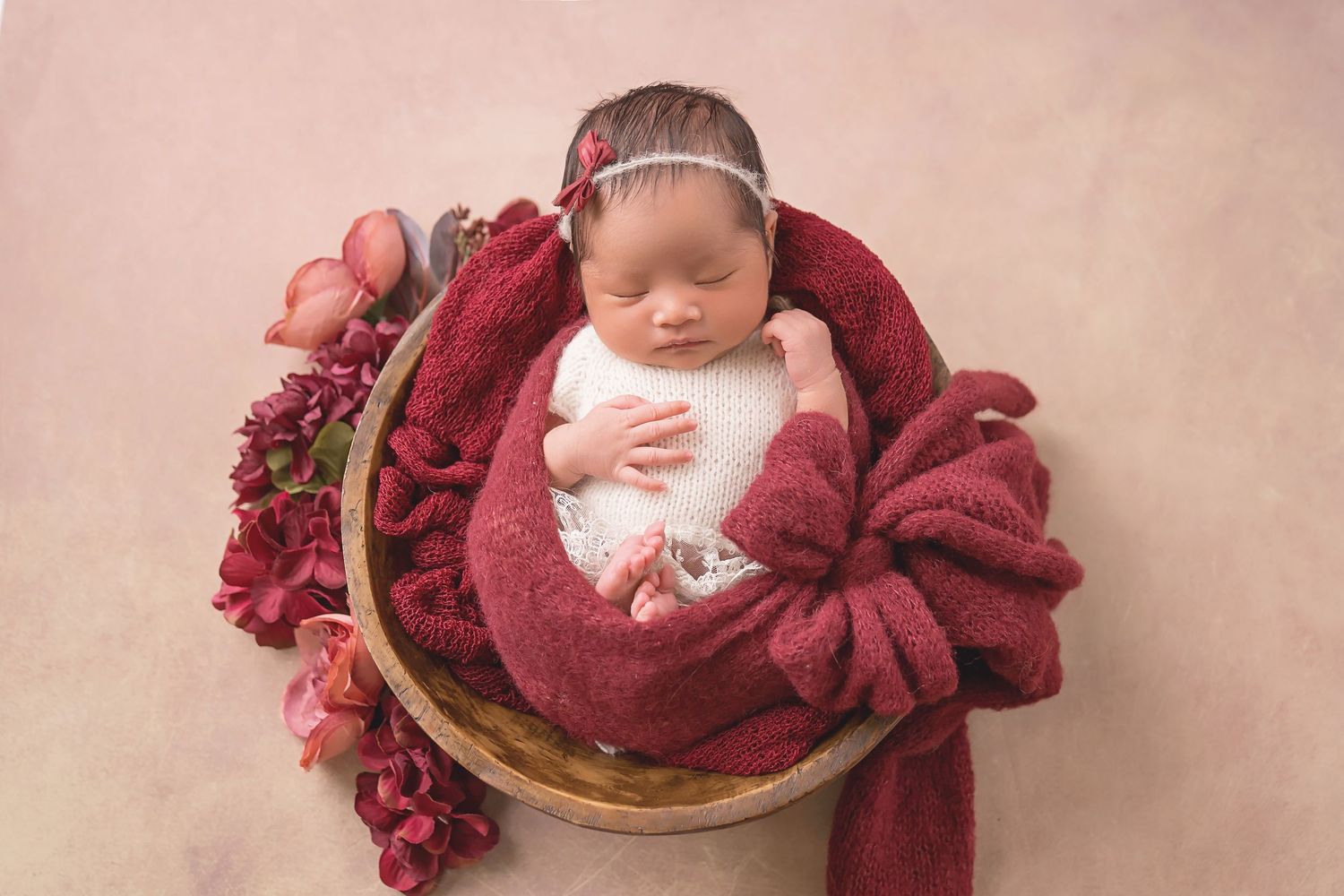 Burgundy fabric and floral elements create rich tones for newborn photography session. San Diego Newborn Photographer