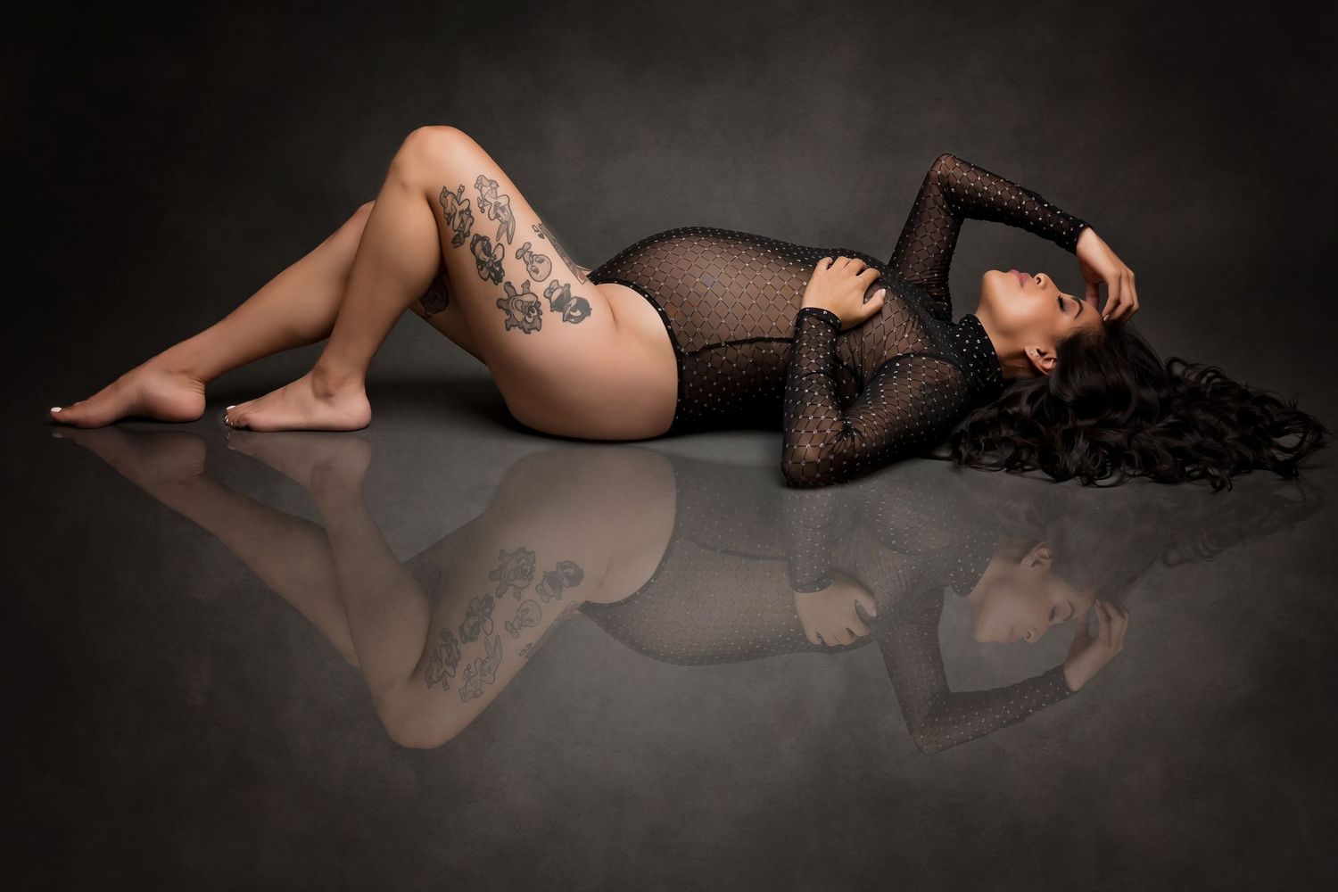 Low-key maternity boudoir portrait with dramatic lighting and sheer fabric