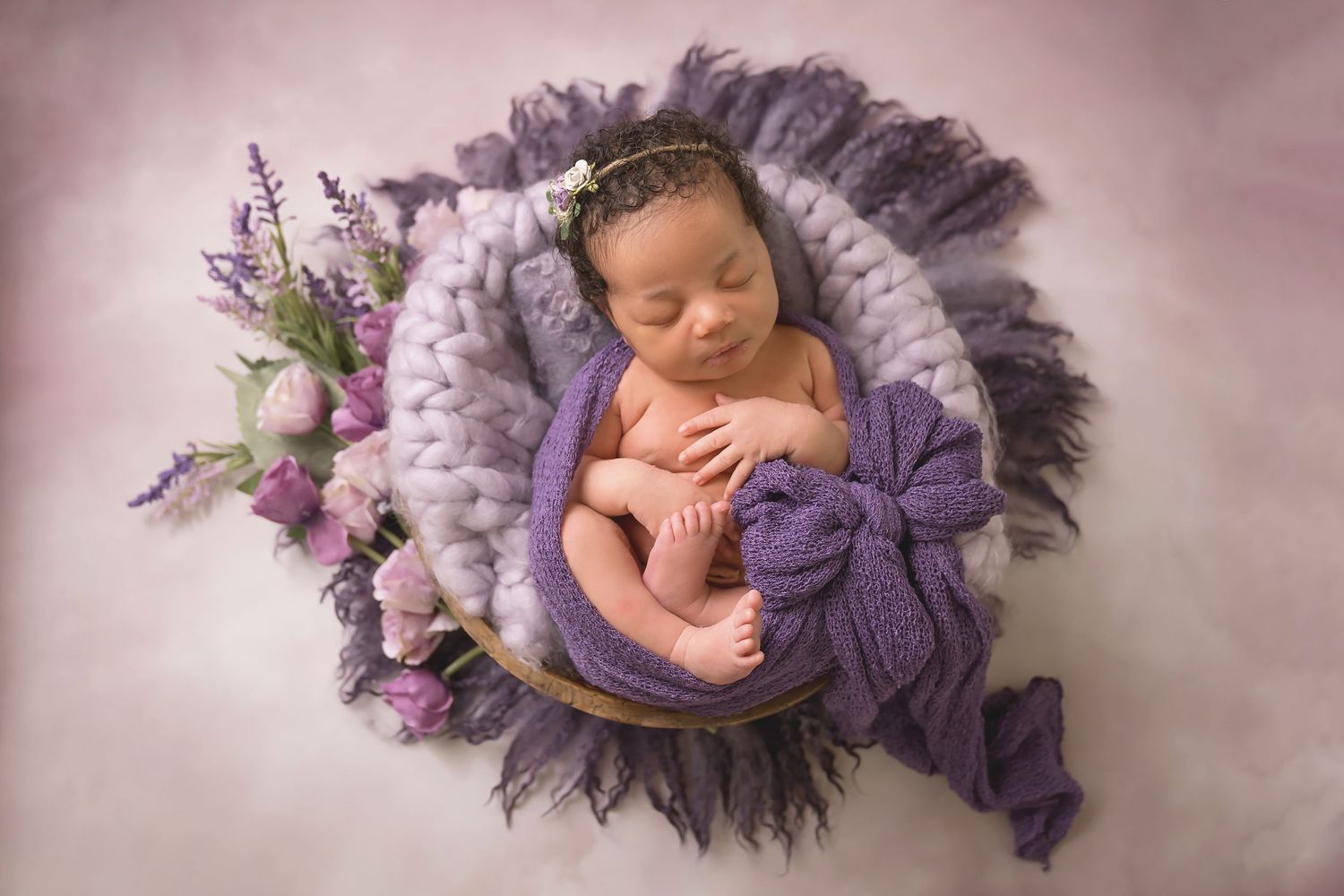 Artistic newborn photography set with purple fabric and lavender floral elements. San Diego Newborn Photographer