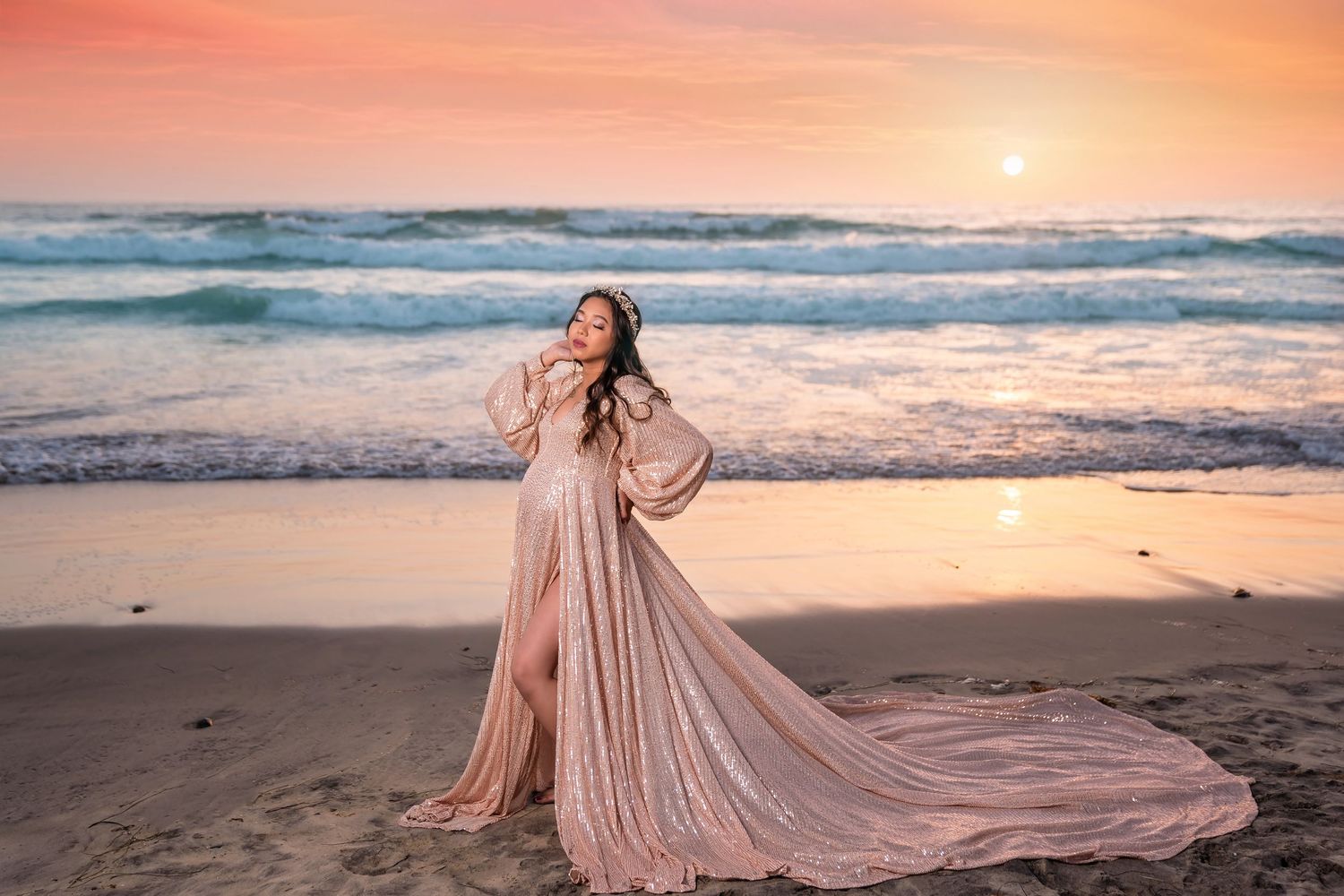 Sunset beach maternity photography session with flowing pink gown creating movement against ocean waves. San Diego Maternity Photographer