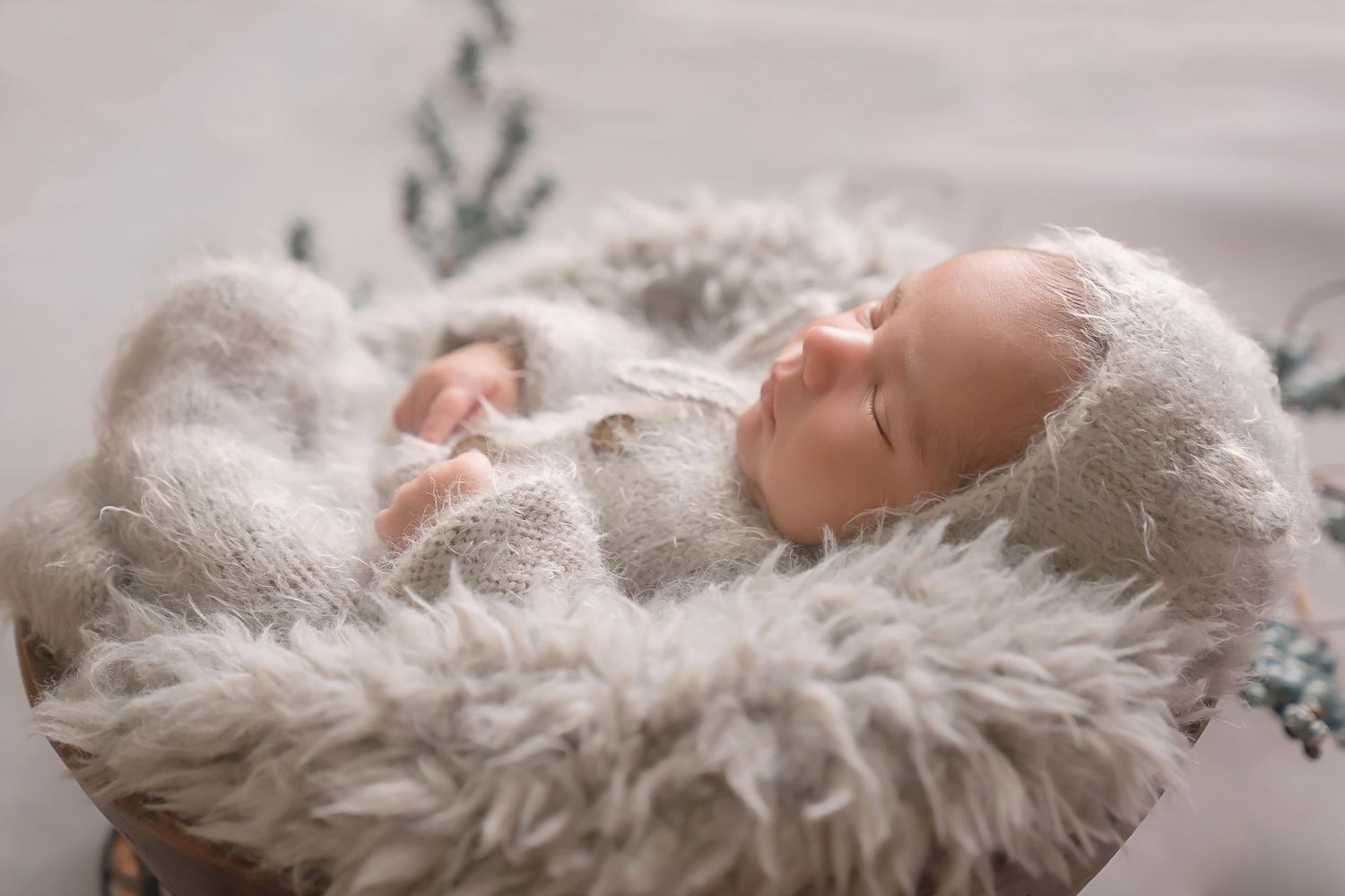 Series of peaceful newborn photos on cozy white fur blanket with greenery accents. San Diego Newborn Photographer