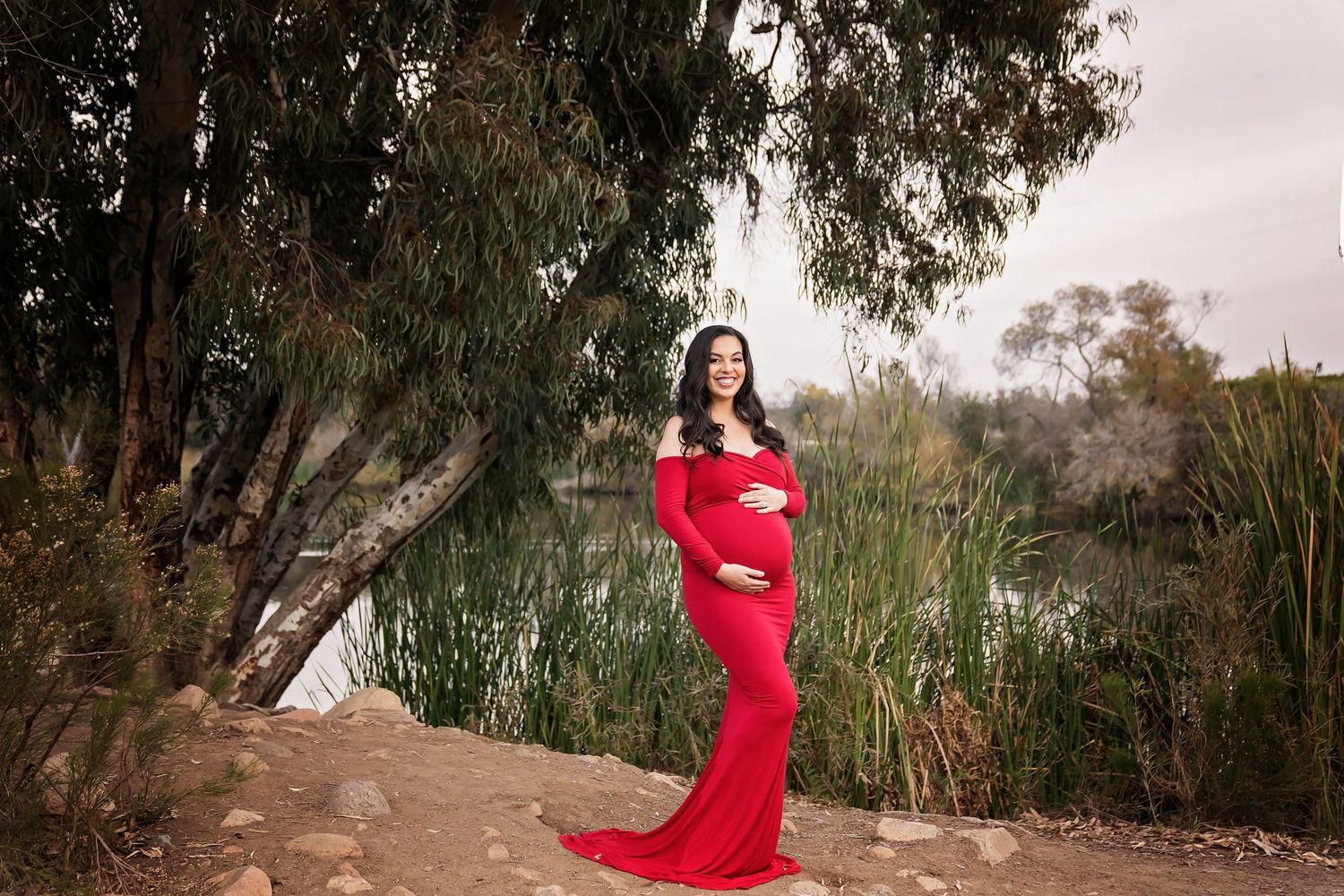 A series of outdoor maternity portraits featuring red flowing dress among trees. San Diego Maternity Photographer