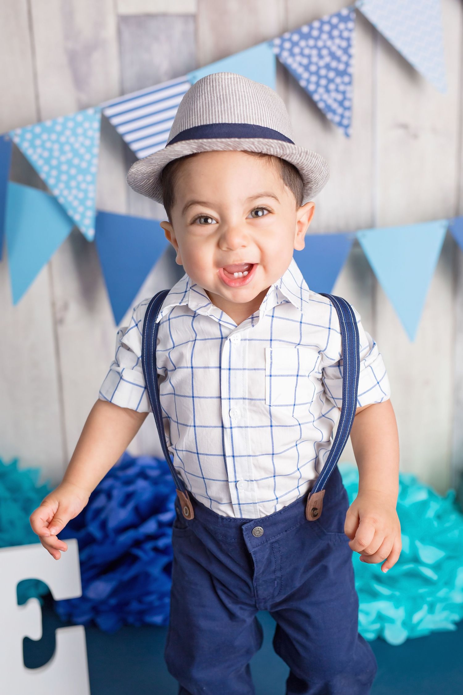 Blue and white bunting decorates a rustic backdrop for a festive photo shoot. San Diego cake smash photographer