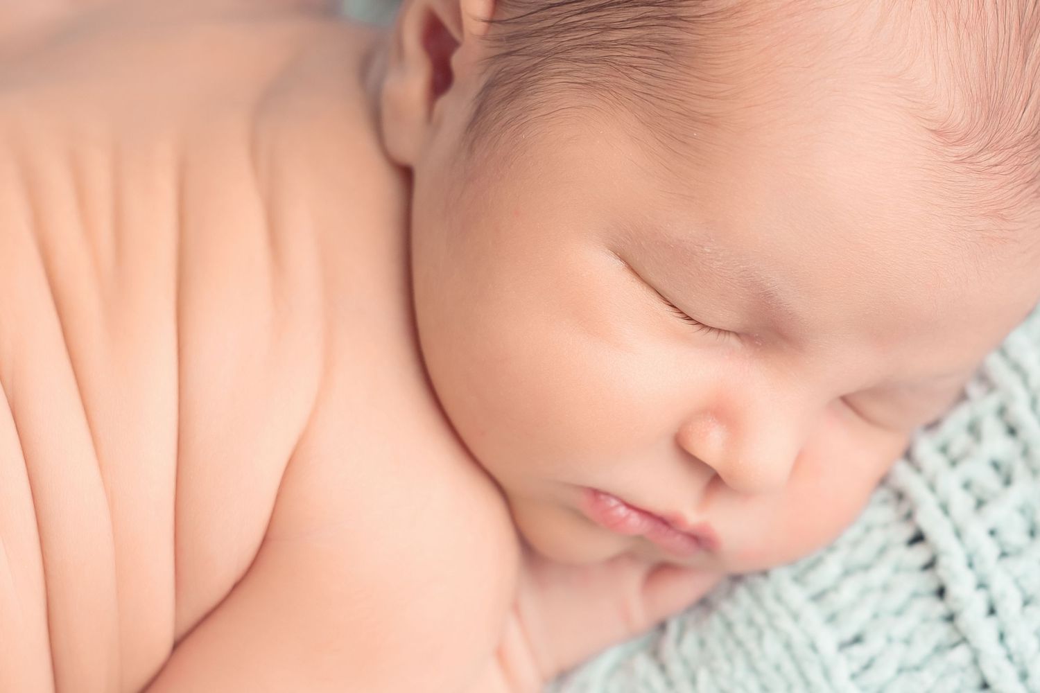 Peaceful closeup of sleeping newborn baby on mint green blanket. San Diego Newborn Photographer