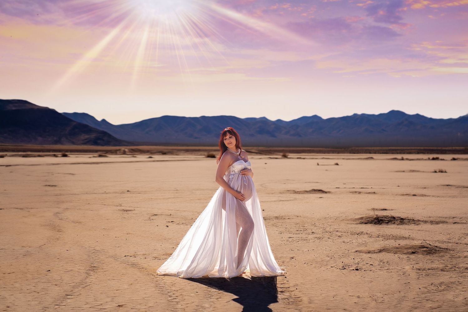 A white dress twirls gracefully in the desert sunlight with mountains in the background. San Diego Maternity Photographer