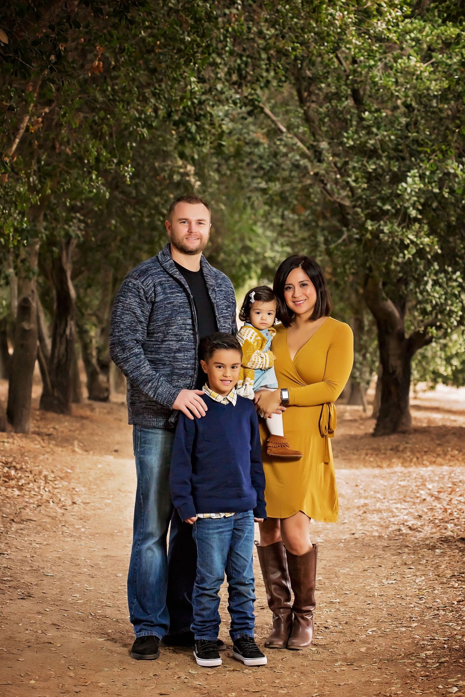 Family of four poses together on woodland path wearing coordinated casual outfits.