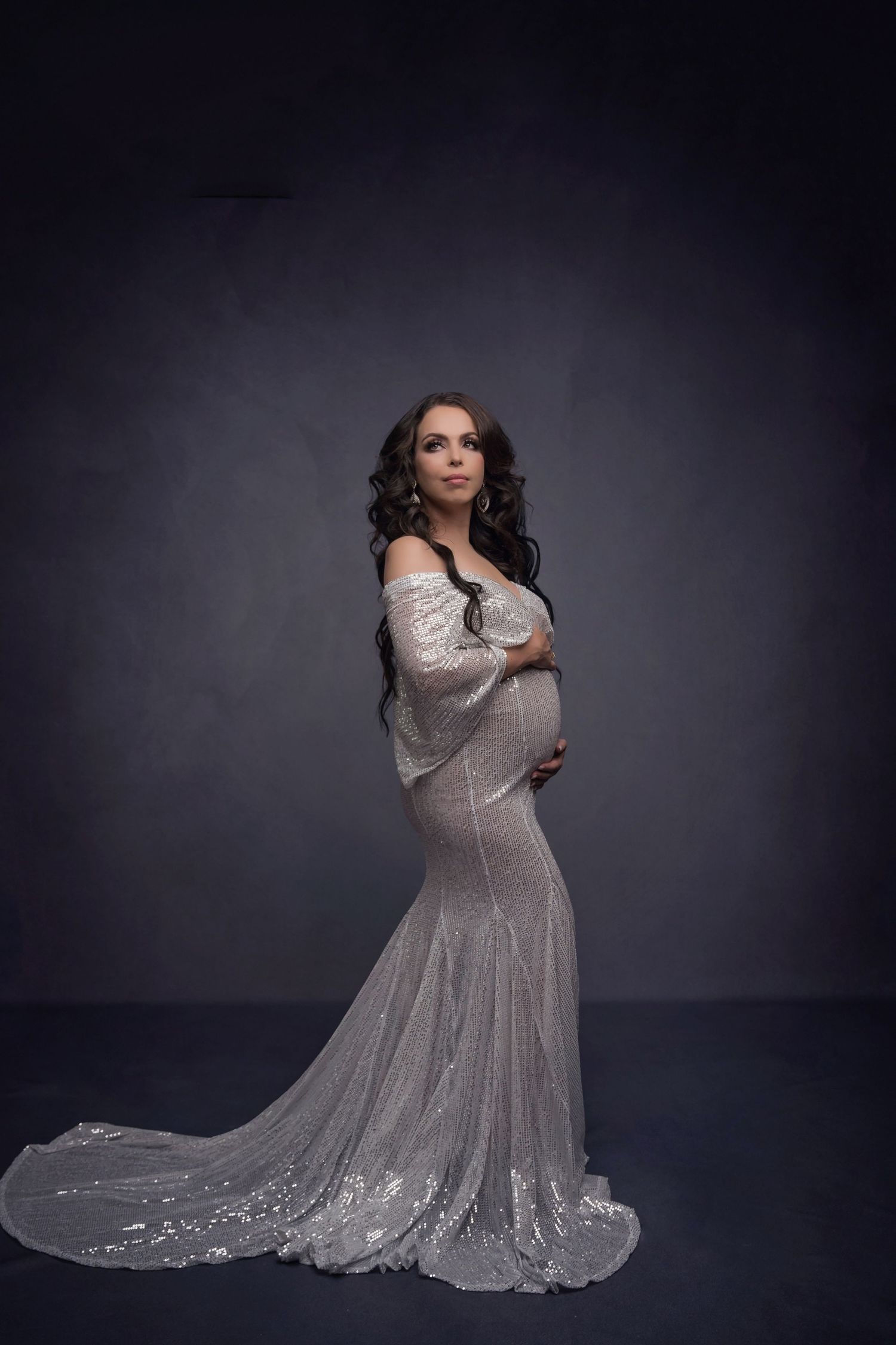 Elegant maternity portrait in sparkly white form-fitting gown with train.