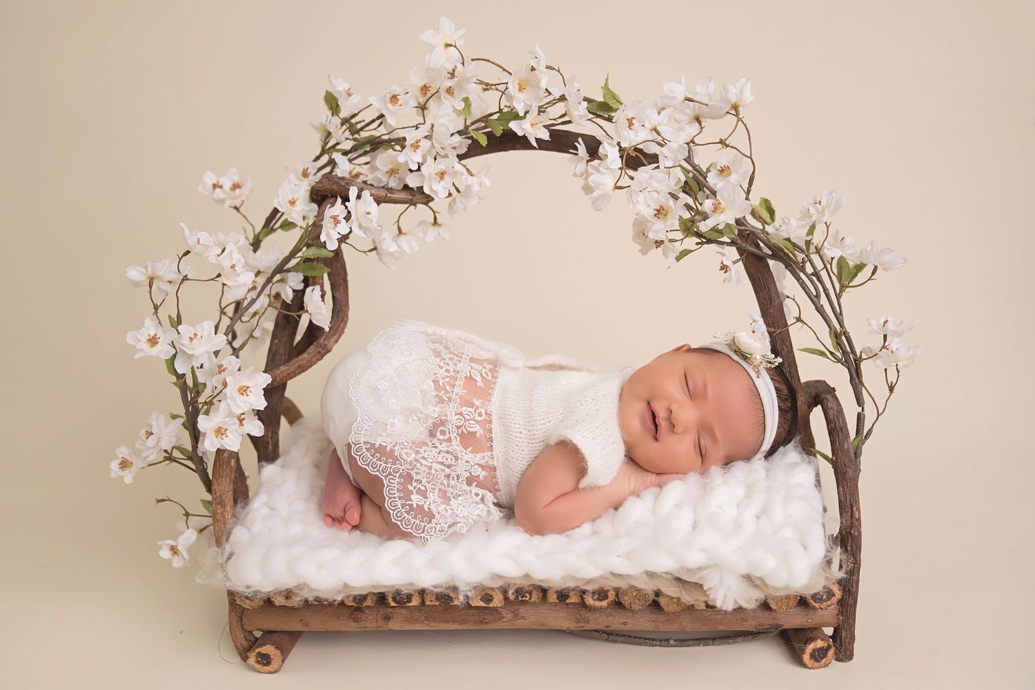 San Diego newborn photographer captures peaceful newborn with white orchids and a rustic wooden prop bed creating a dreamy atmosphere.