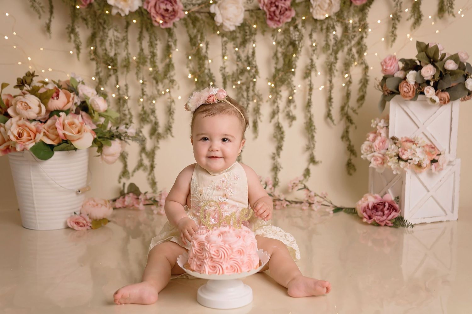Elegant birthday setup with pink roses, hanging greenery and white decorative elements. San Diego cake smash photographer