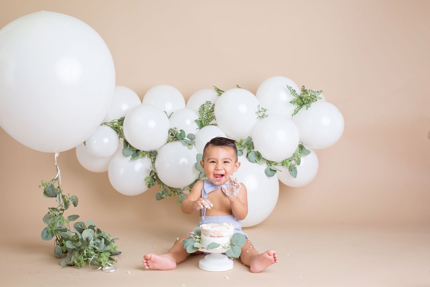 San Diego cake smash set up with White balloon arch with eucalyptus leaves creates an elegant photography backdrop.
