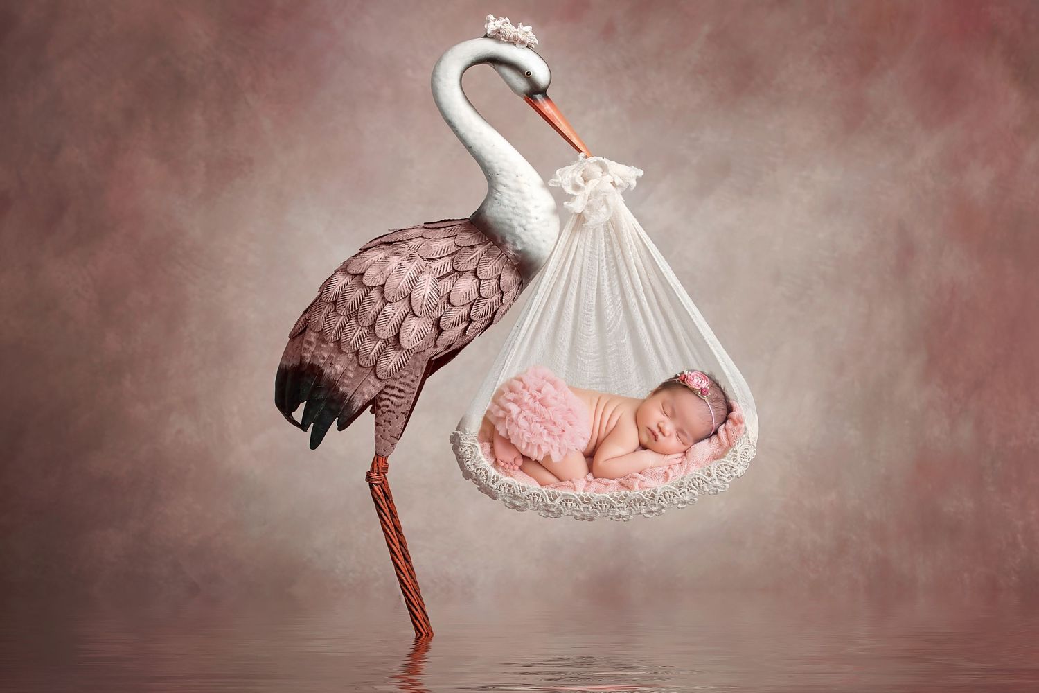 Newborn baby sleeping in a white sack held by a stork, classic baby delivery concept on pink background.