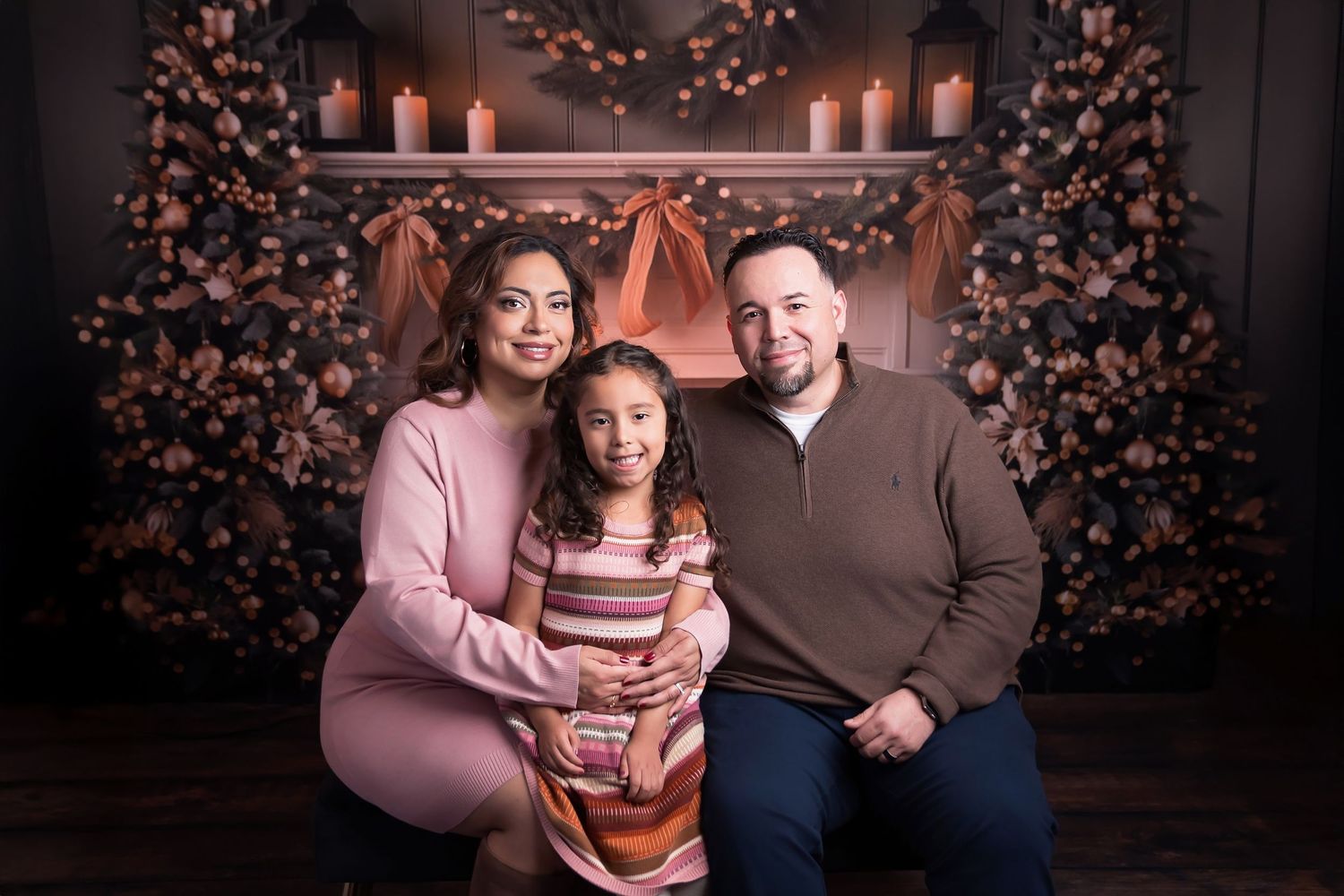 San Diego Holiday Mini Sessions Family poses together in front of a decorated holiday backdrop with glowing lights and floral arrangements.