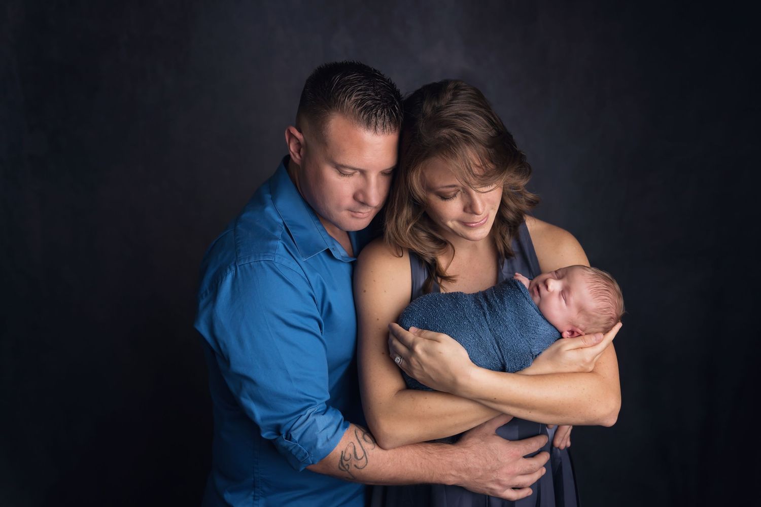 Intimate family portrait session showing tender moments in blue tones and dramatic lighting. San Diego Newborn Photographer