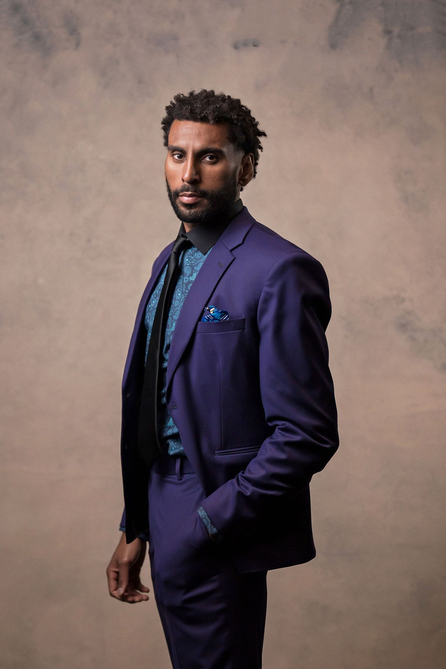 Professional portrait of man wearing a purple blazer against a textured studio backdrop