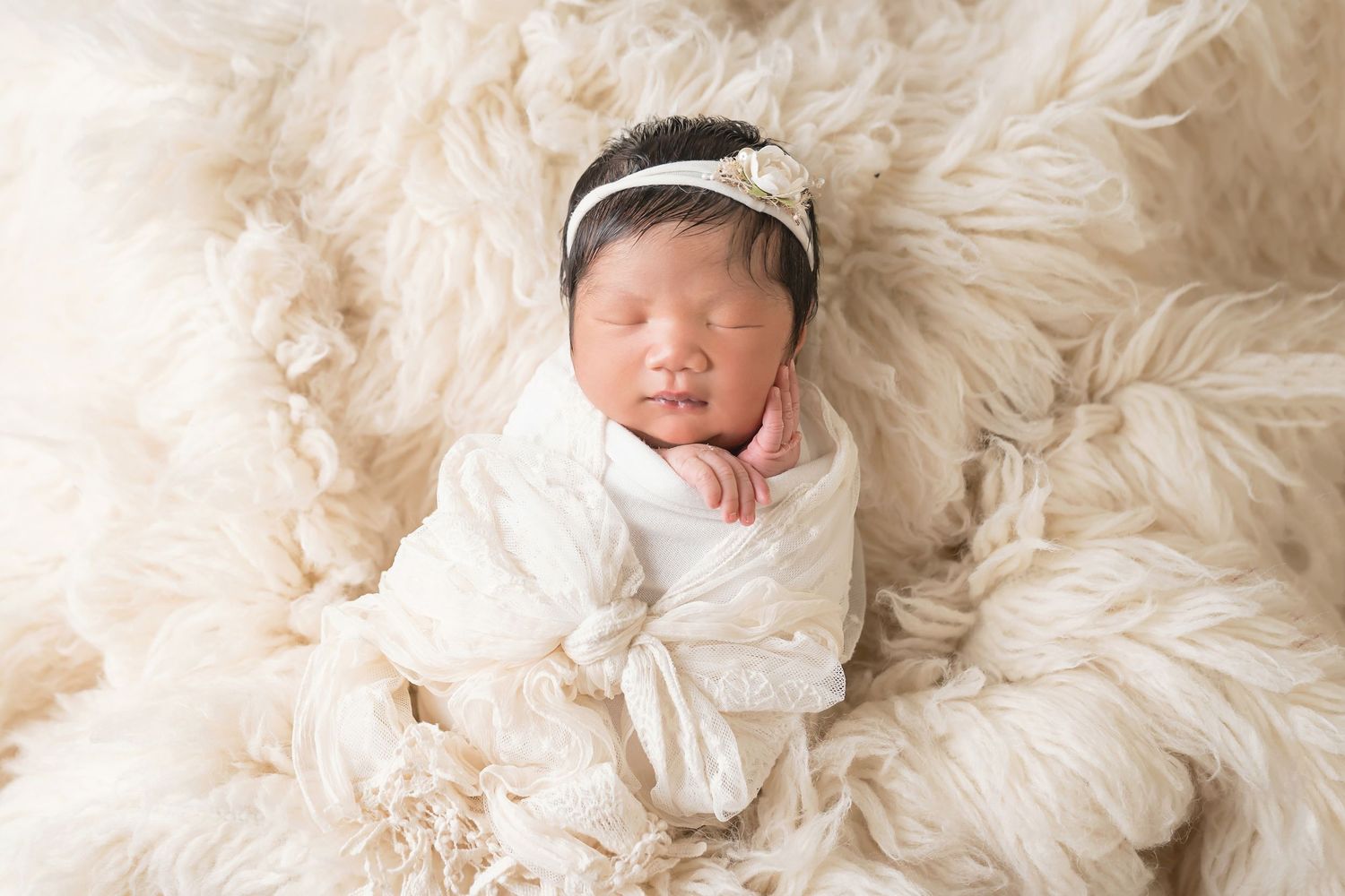 Delicate newborn portrait with white lace wrap against cream textured background. San Diego Newborn Photographer
