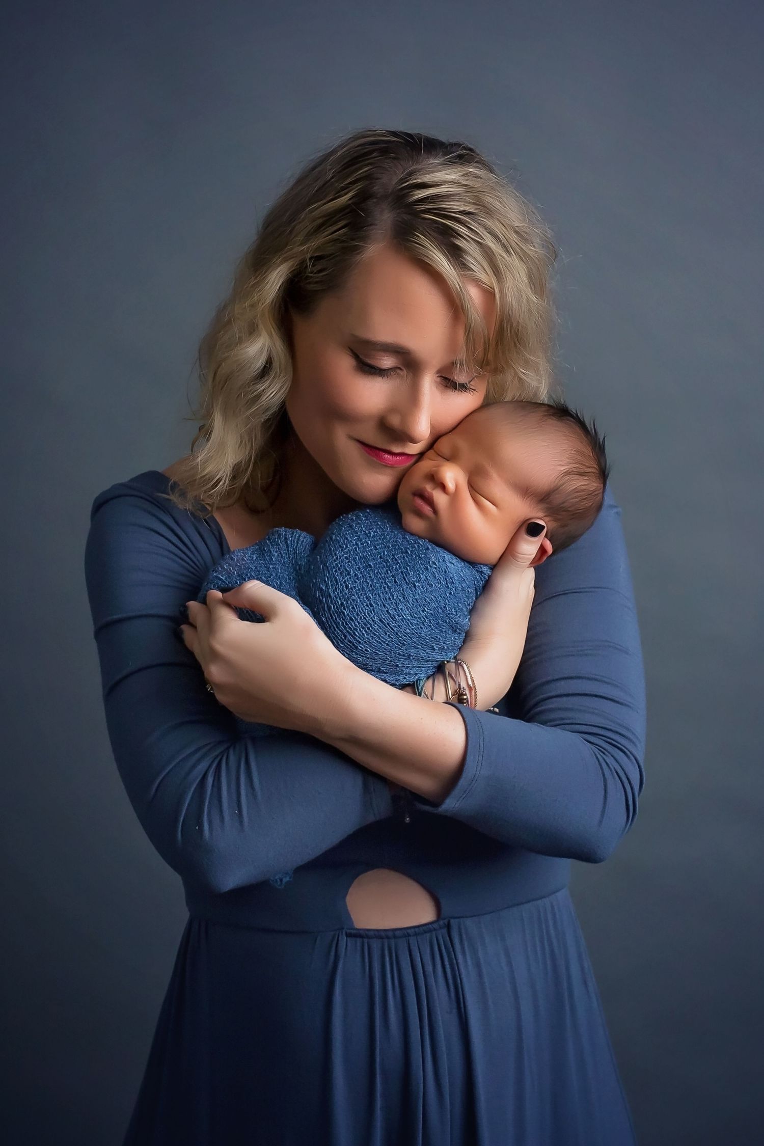 Emotional portrait series in navy blue dress against dark background. San Diego Newborn Photographer