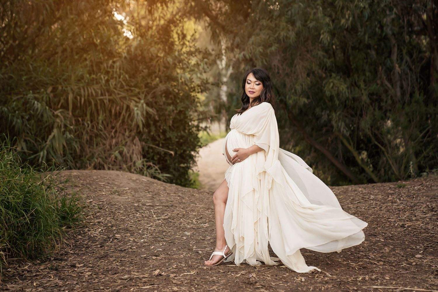 Outdoor maternity photoshoot featuring flowing white dress against natural backdrop. San Diego Maternity Photographer