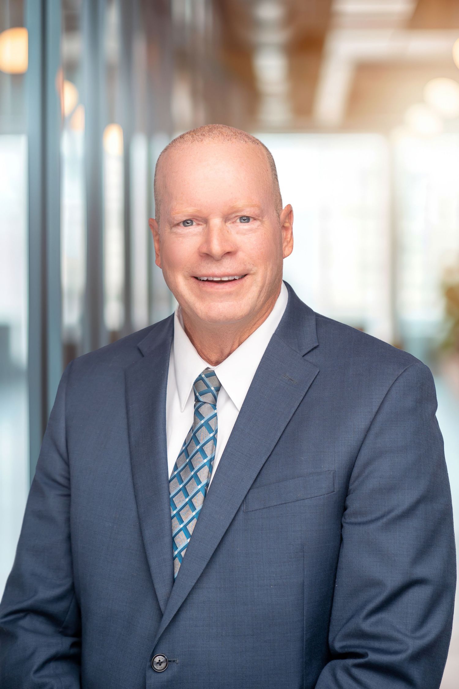 Business portrait of man in grey suit and patterned tie with bright office-style background