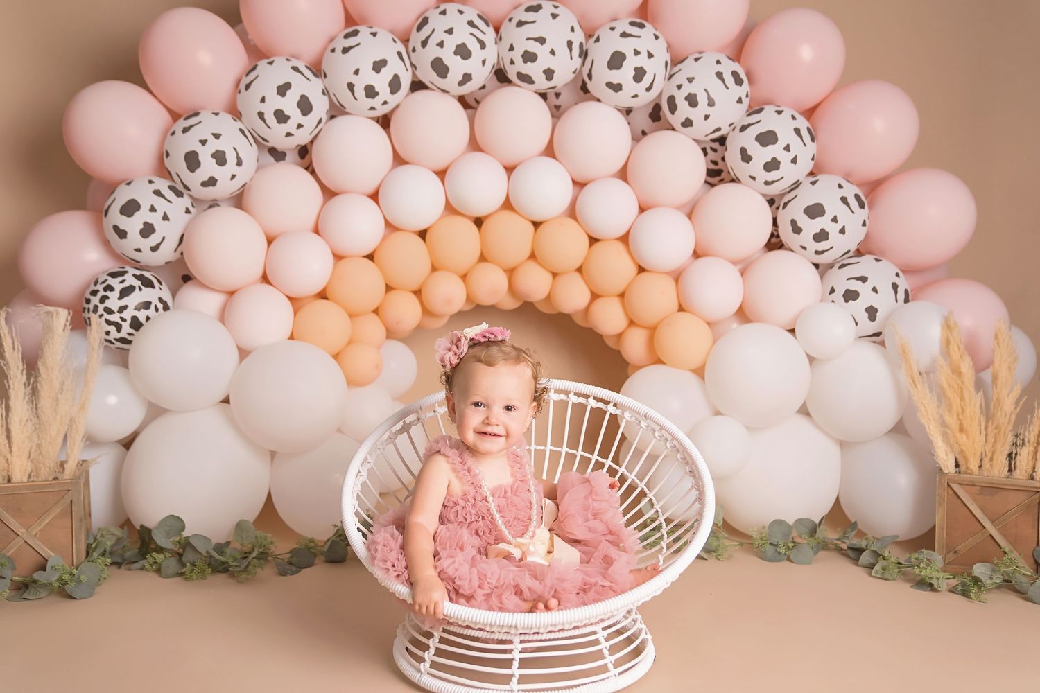 San Diego first birthday photo set up with Pink balloon arch with white accents and wicker chair setup. San Diego cake smash photographer