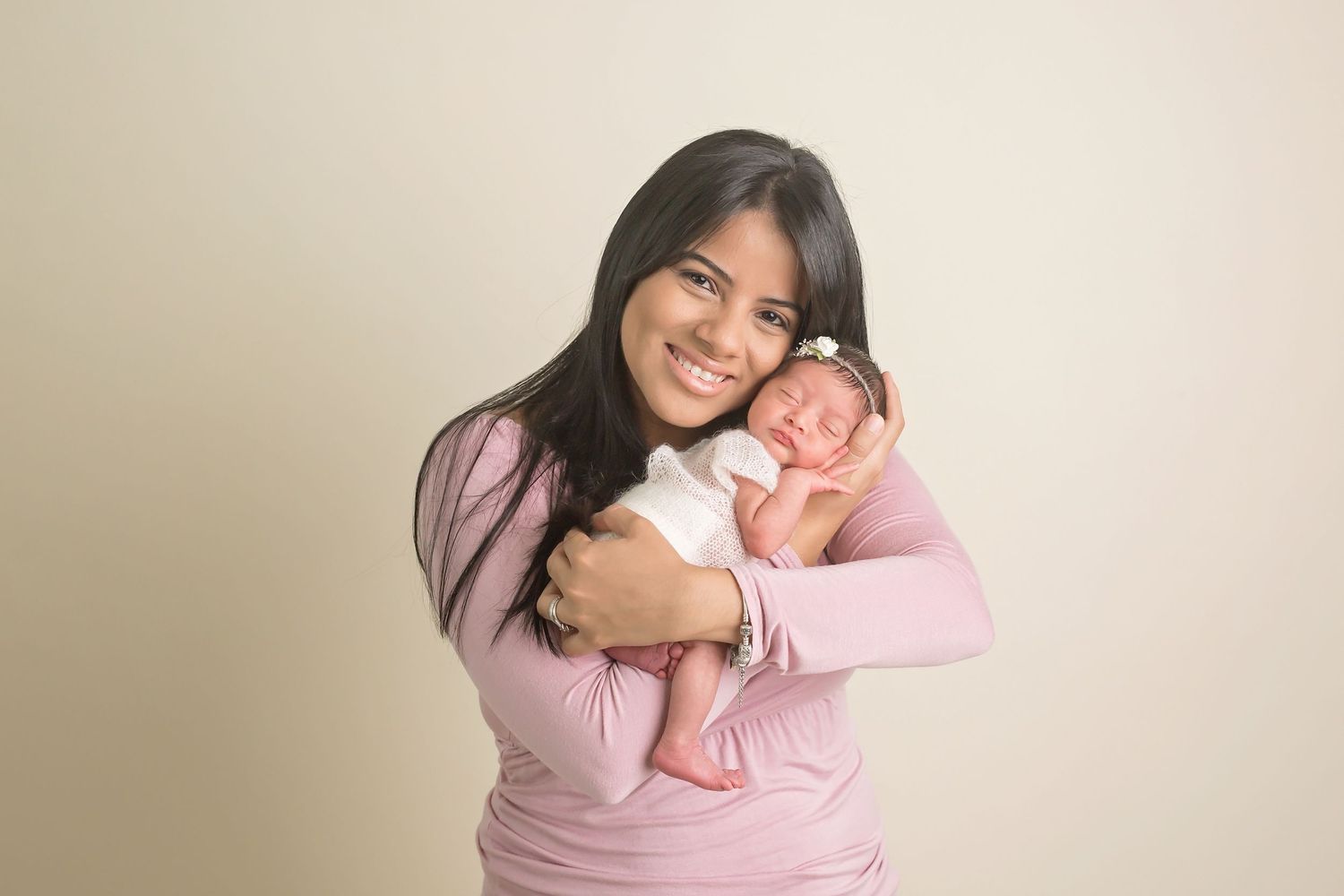 Tender family moment with newborn baby wrapped in pink against neutral background. San Diego Newborn Photographer